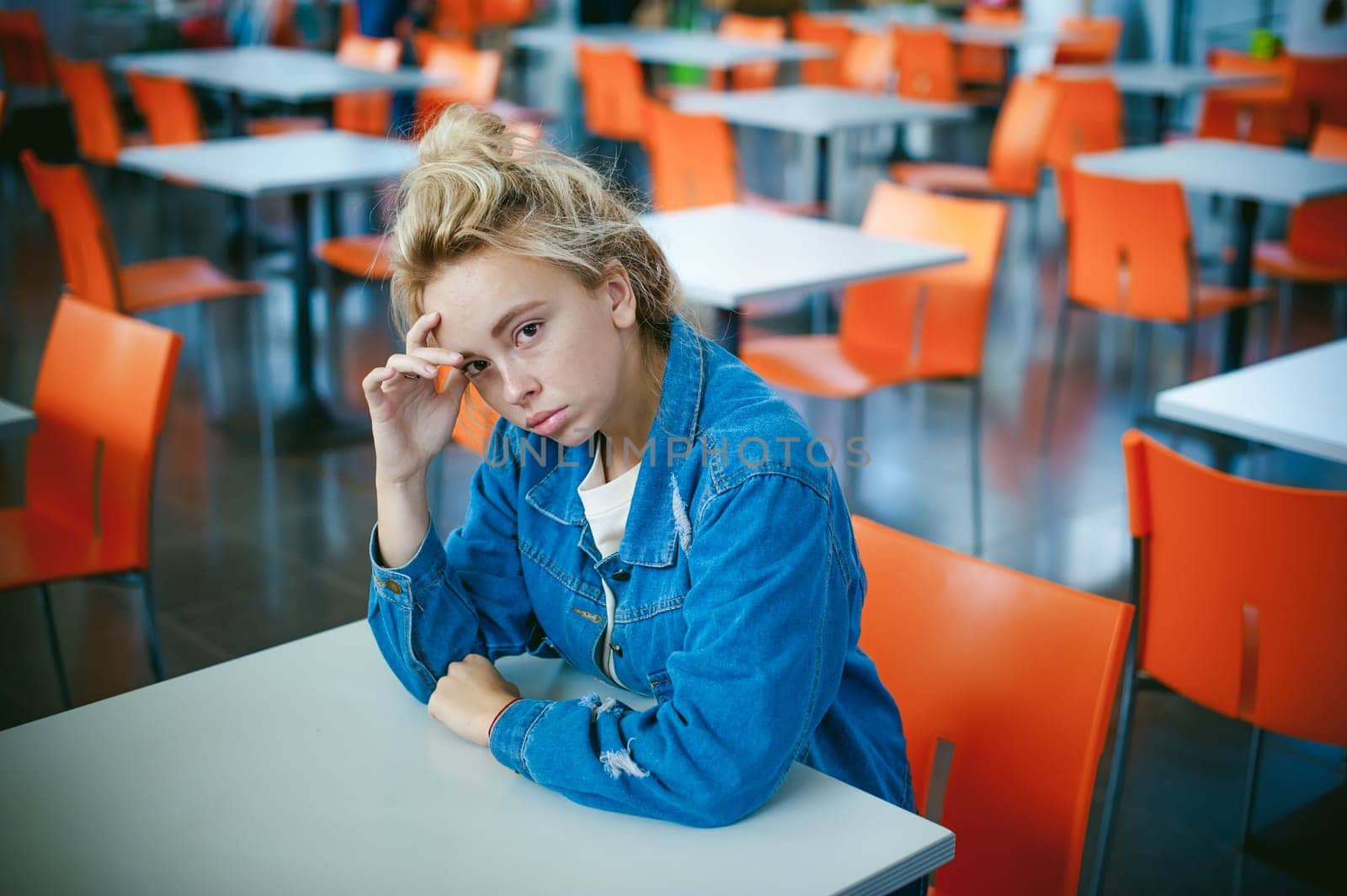young beautiful woman in jeans clothes in business space of shopping center. portrait of a girl with freckles on her face, stylish girl in an empty cafe