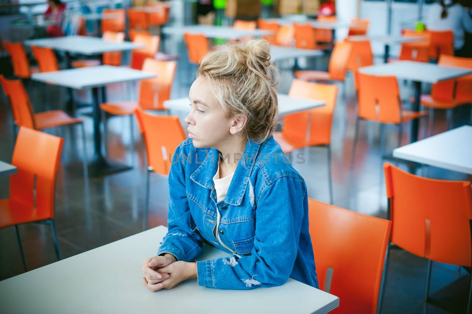 young beautiful woman in jeans clothes in business space of shopping center. portrait of a girl with freckles on her face, stylish girl in an empty cafe