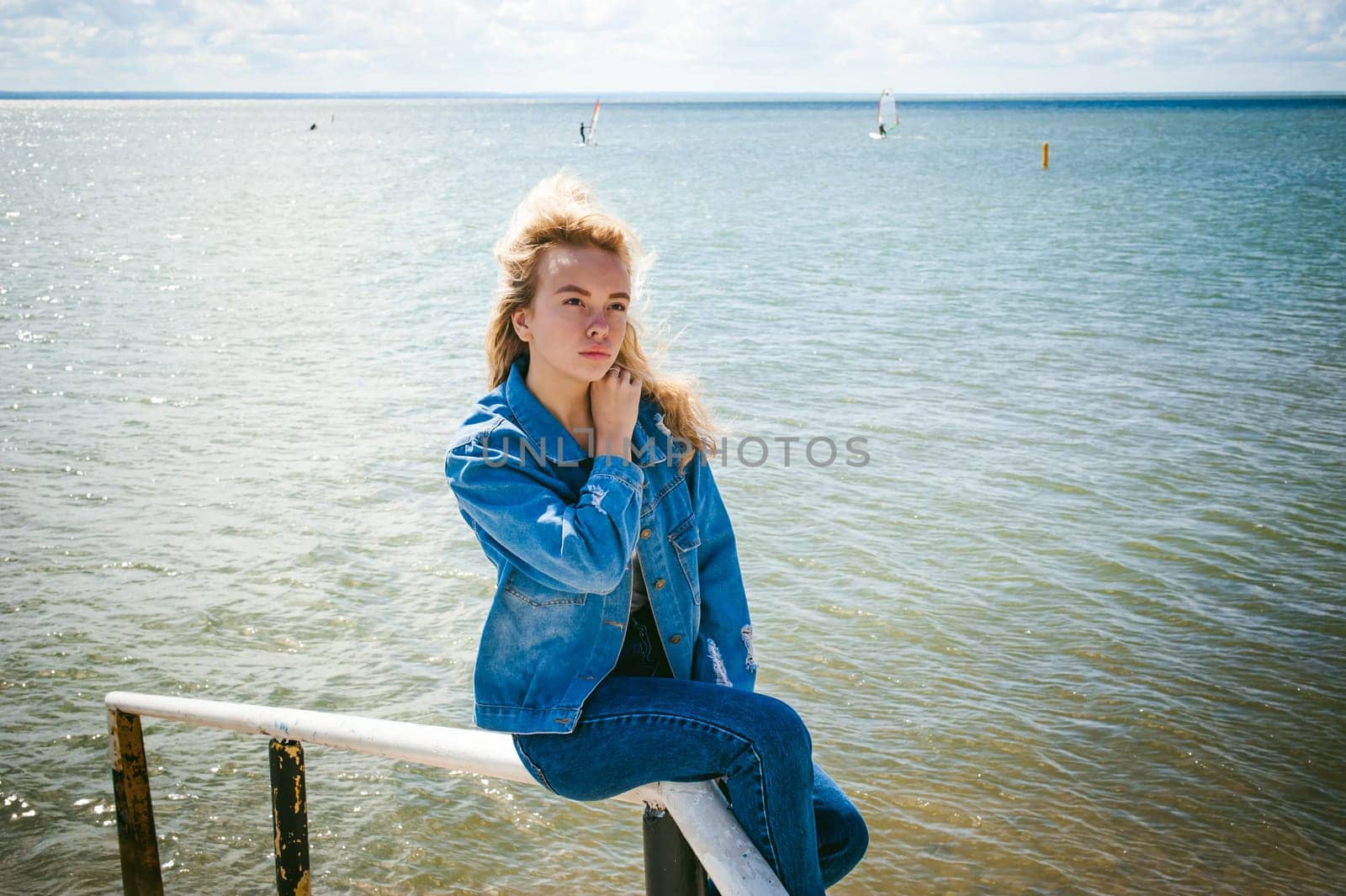 young beautiful woman in jeans clothes outdoors. portrait of a girl with freckles on her face, stylish girl on sea beach, on a sunny summer autumn day.