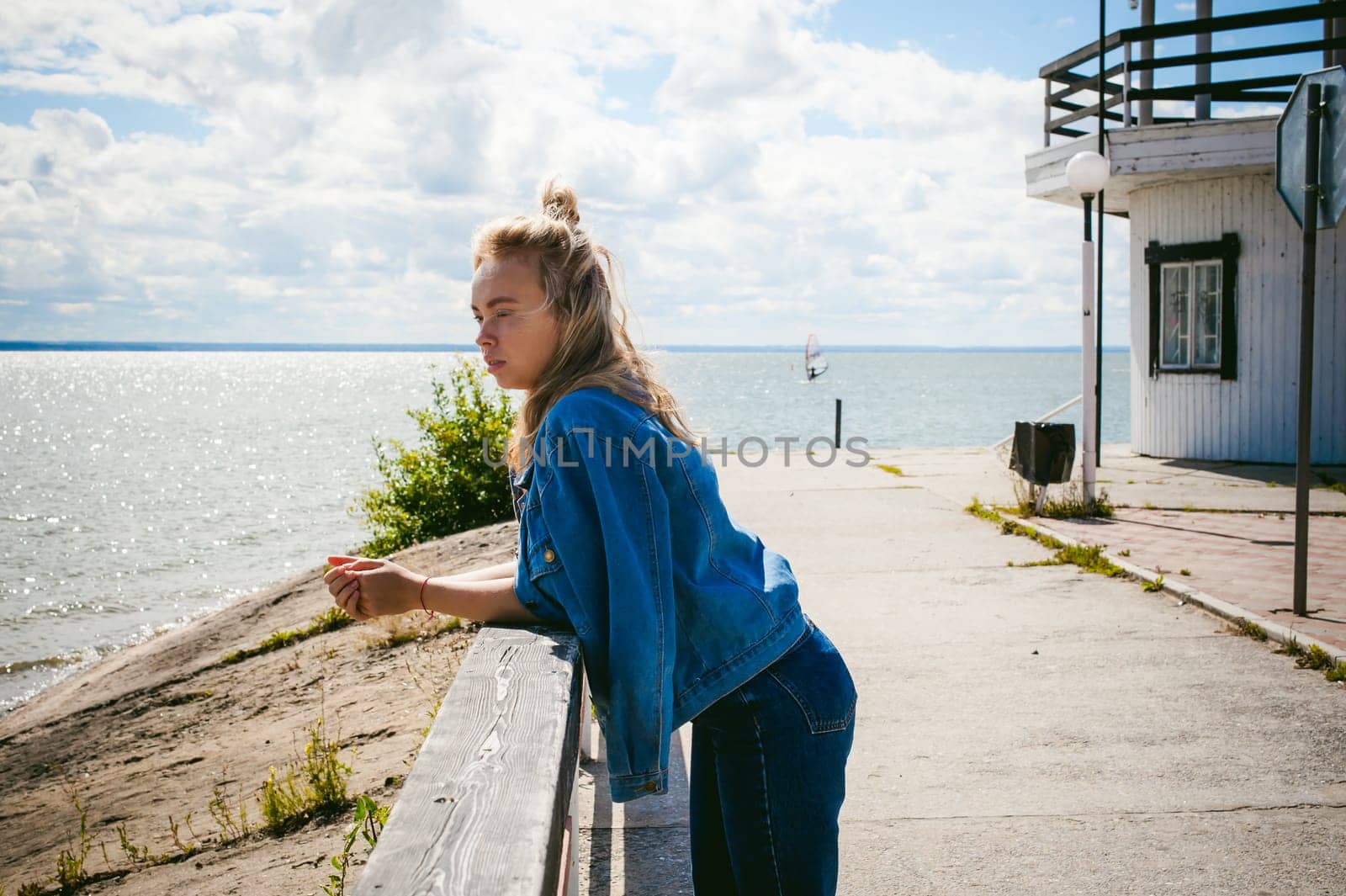 young beautiful woman in jeans clothes outdoors. portrait of a girl with freckles on her face, stylish girl on sea beach, on a sunny summer autumn day.