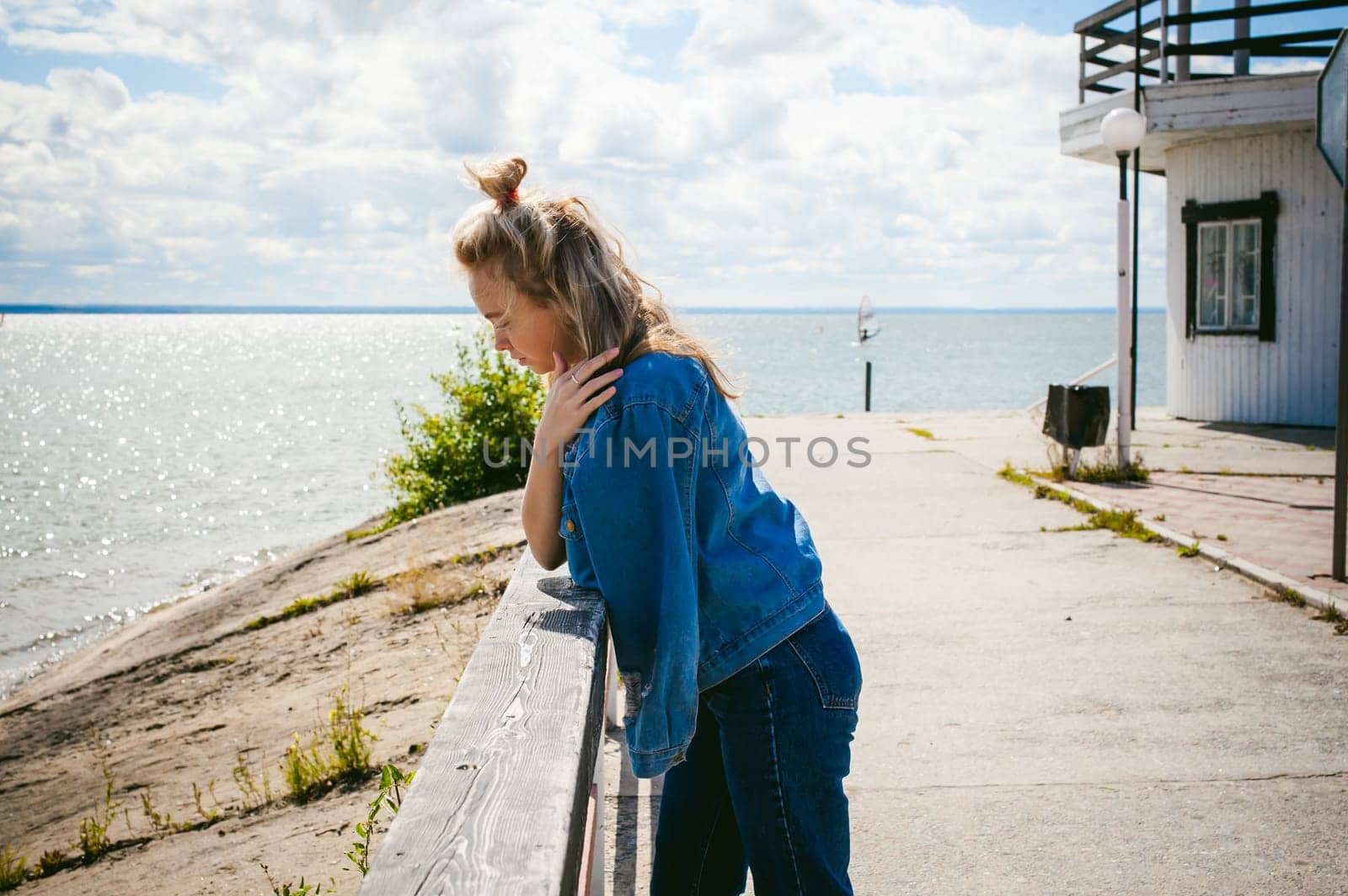 young beautiful woman in jeans clothes outdoors. portrait of a girl with freckles on her face, stylish girl on sea beach, on a sunny summer autumn day.