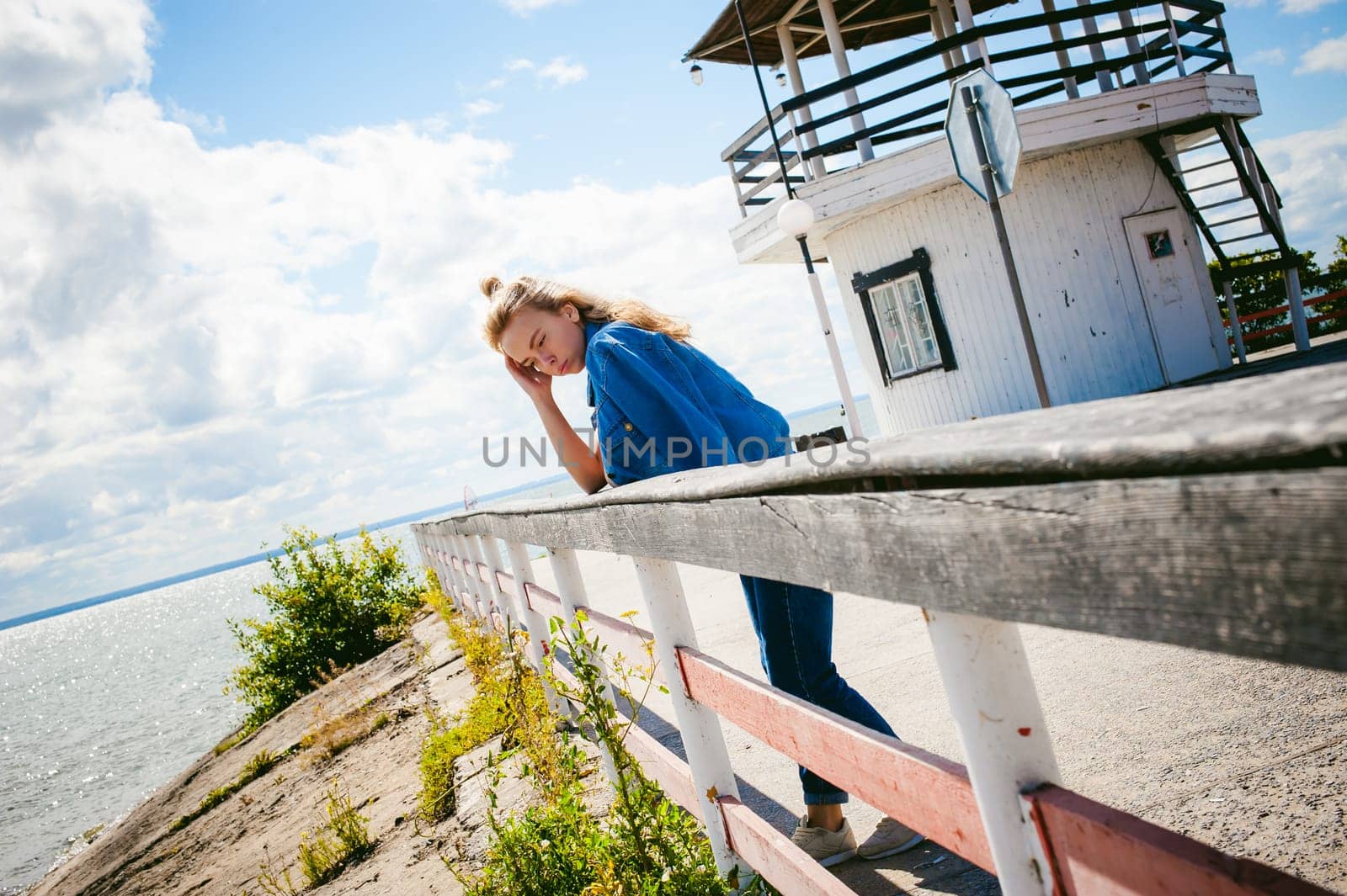 young beautiful woman in jeans clothes outdoors. portrait of a girl with freckles on her face, stylish girl on sea beach, on a sunny summer autumn day.