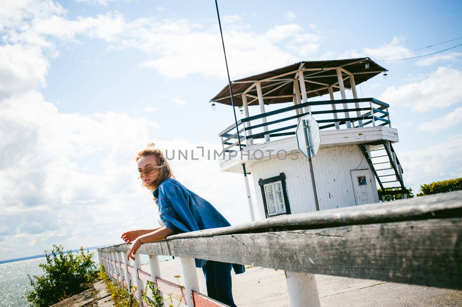 young beautiful woman in jeans clothes outdoors. portrait of a girl with freckles on her face, stylish girl on sea beach, on a sunny summer autumn day.