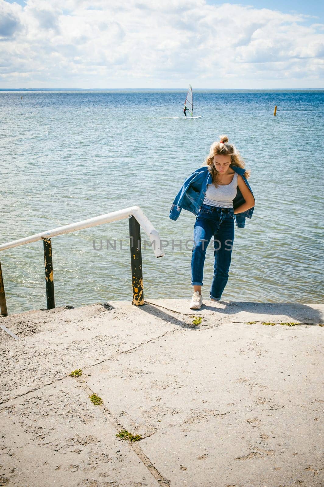 young beautiful woman in jeans clothes outdoors. portrait of a girl with freckles on her face, stylish girl on sea beach, on a sunny summer autumn day.