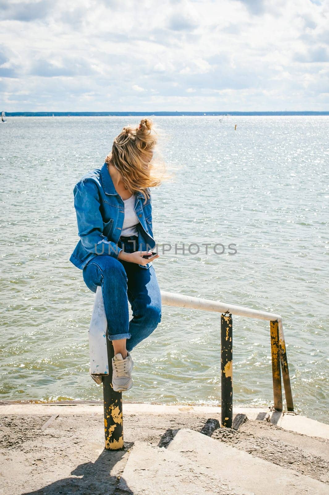 young beautiful woman in jeans clothes outdoors. portrait of a girl with freckles on her face, stylish girl on sea beach, on a sunny summer autumn day.