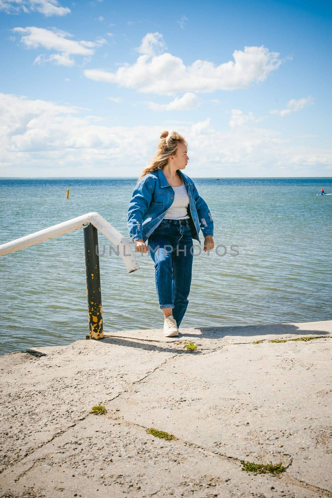 young beautiful woman in jeans clothes outdoors. portrait of a girl with freckles on her face, stylish girl on sea beach, on a sunny summer autumn day.