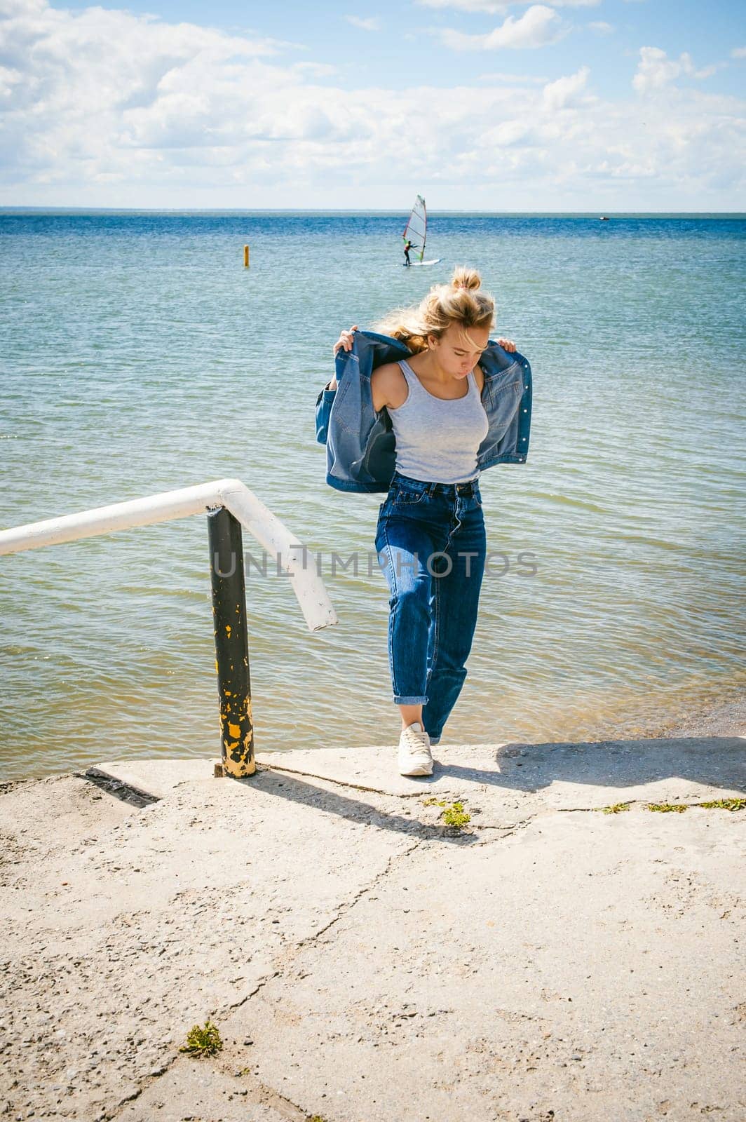 young beautiful woman in jeans clothes outdoors. portrait of a girl with freckles on her face, stylish girl on sea beach, on a sunny summer autumn day.