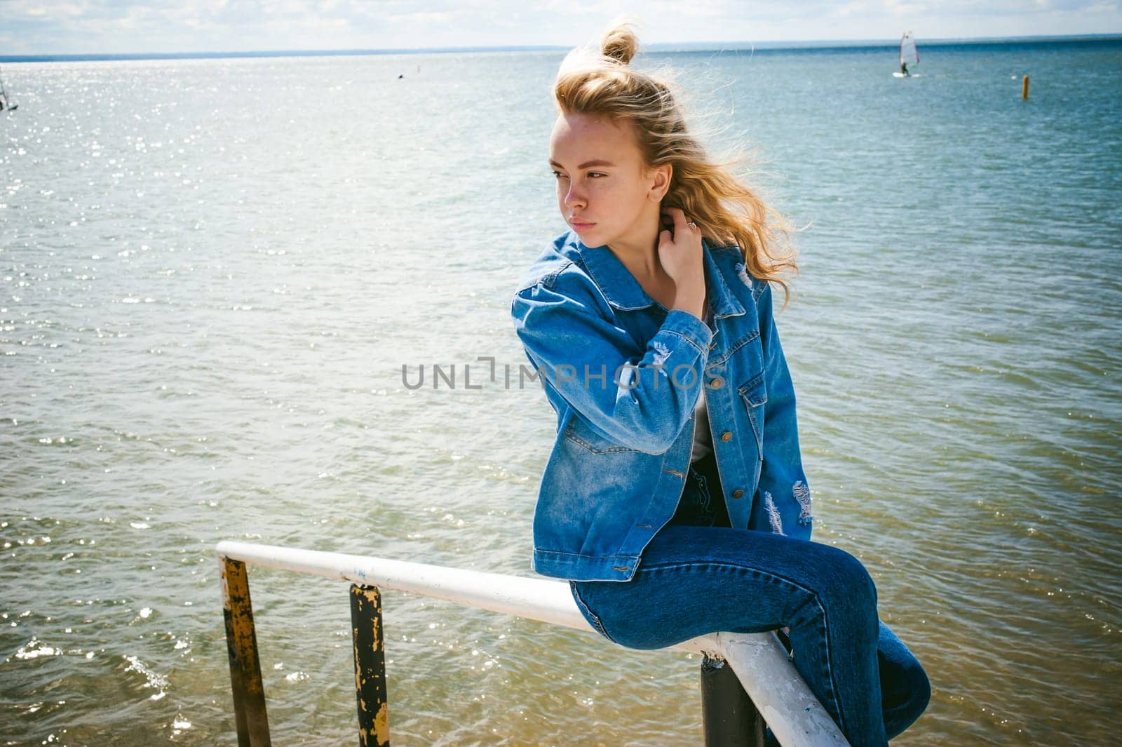 young beautiful woman in jeans clothes outdoors. portrait of a girl with freckles on her face, stylish girl on sea beach, on a sunny summer autumn day.