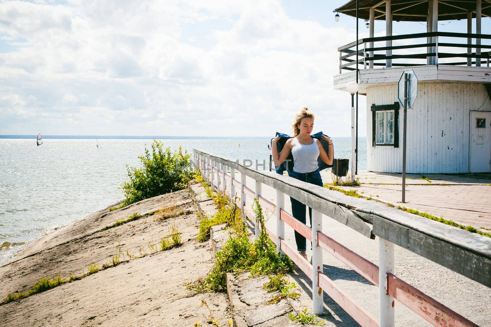 young beautiful woman in jeans clothes outdoors. portrait of a girl with freckles on her face, stylish girl on sea beach, on a sunny summer autumn day.