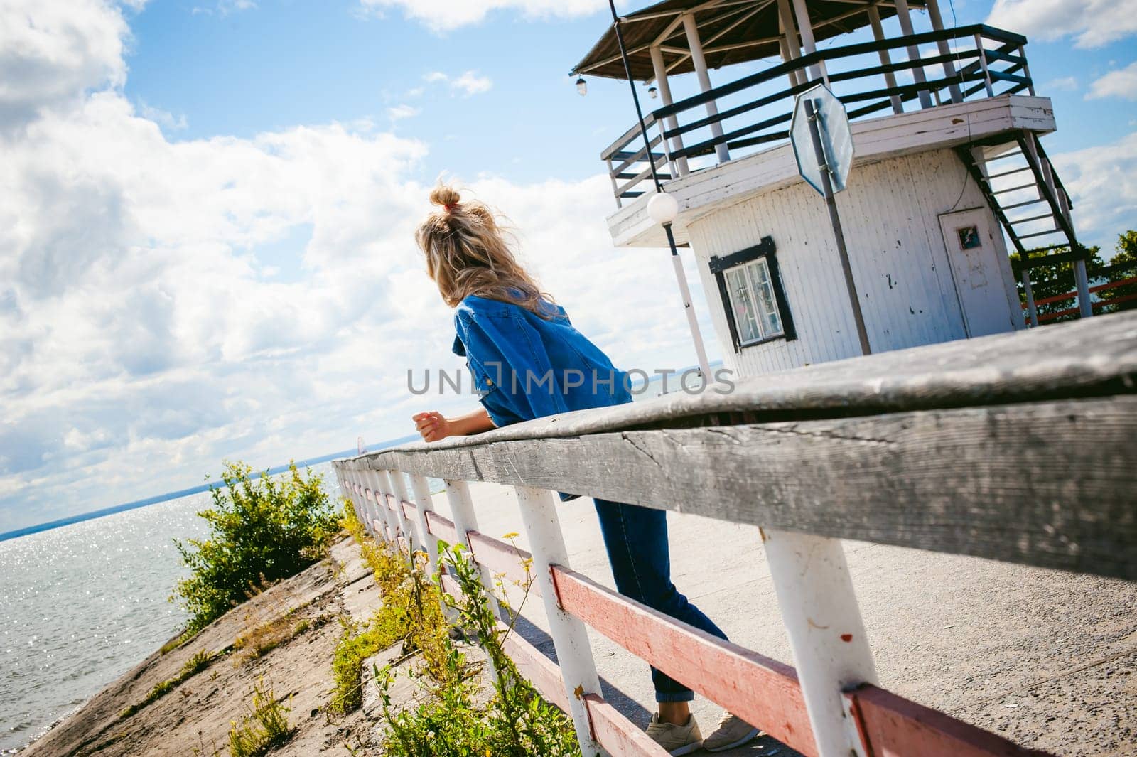 young beautiful woman in jeans clothes outdoors. portrait of a girl with freckles on her face, stylish girl on sea beach, on a sunny summer autumn day.