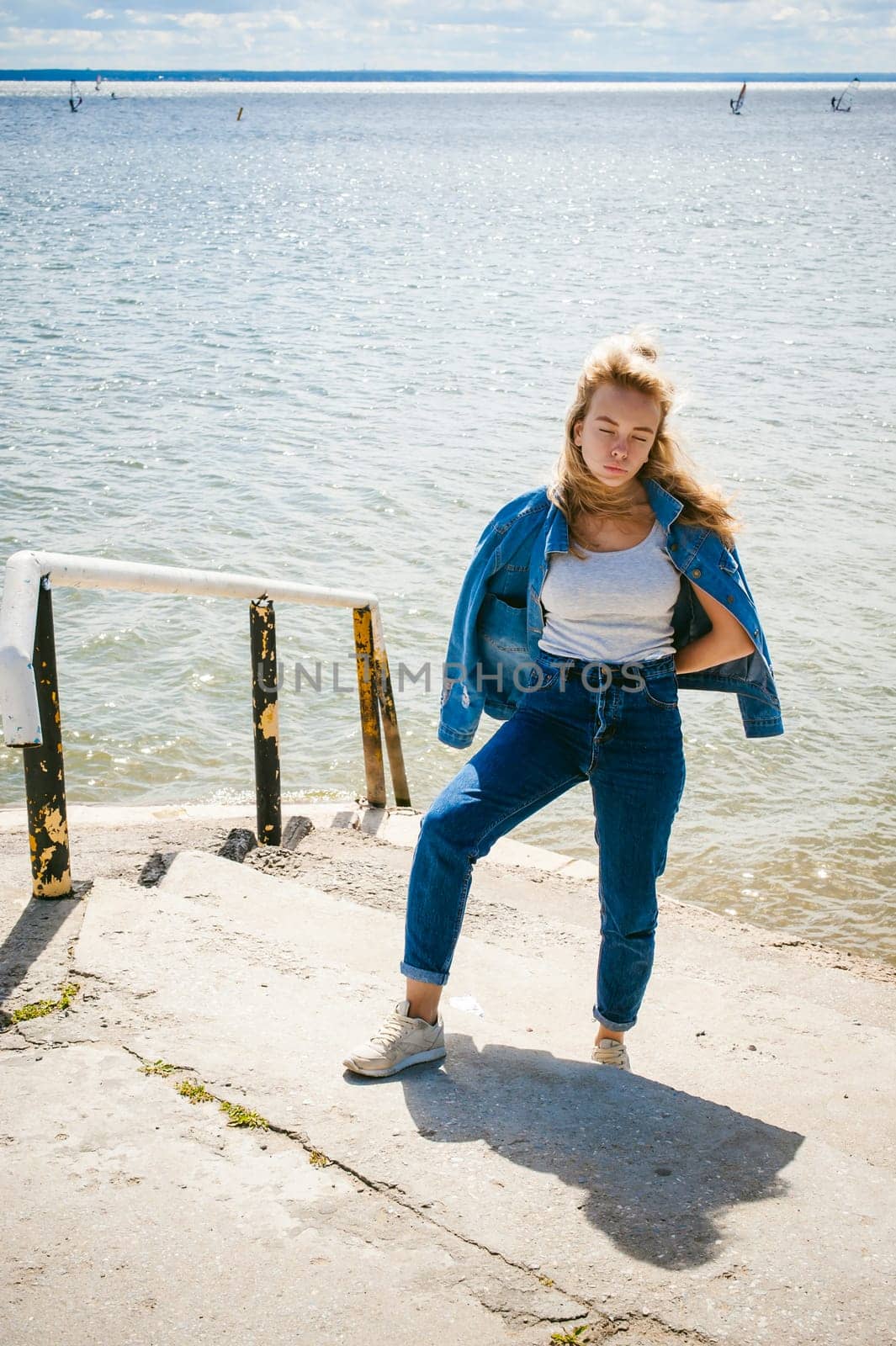 young beautiful woman in jeans clothes outdoors. portrait of a girl with freckles on her face, stylish girl on sea beach, on a sunny summer autumn day.