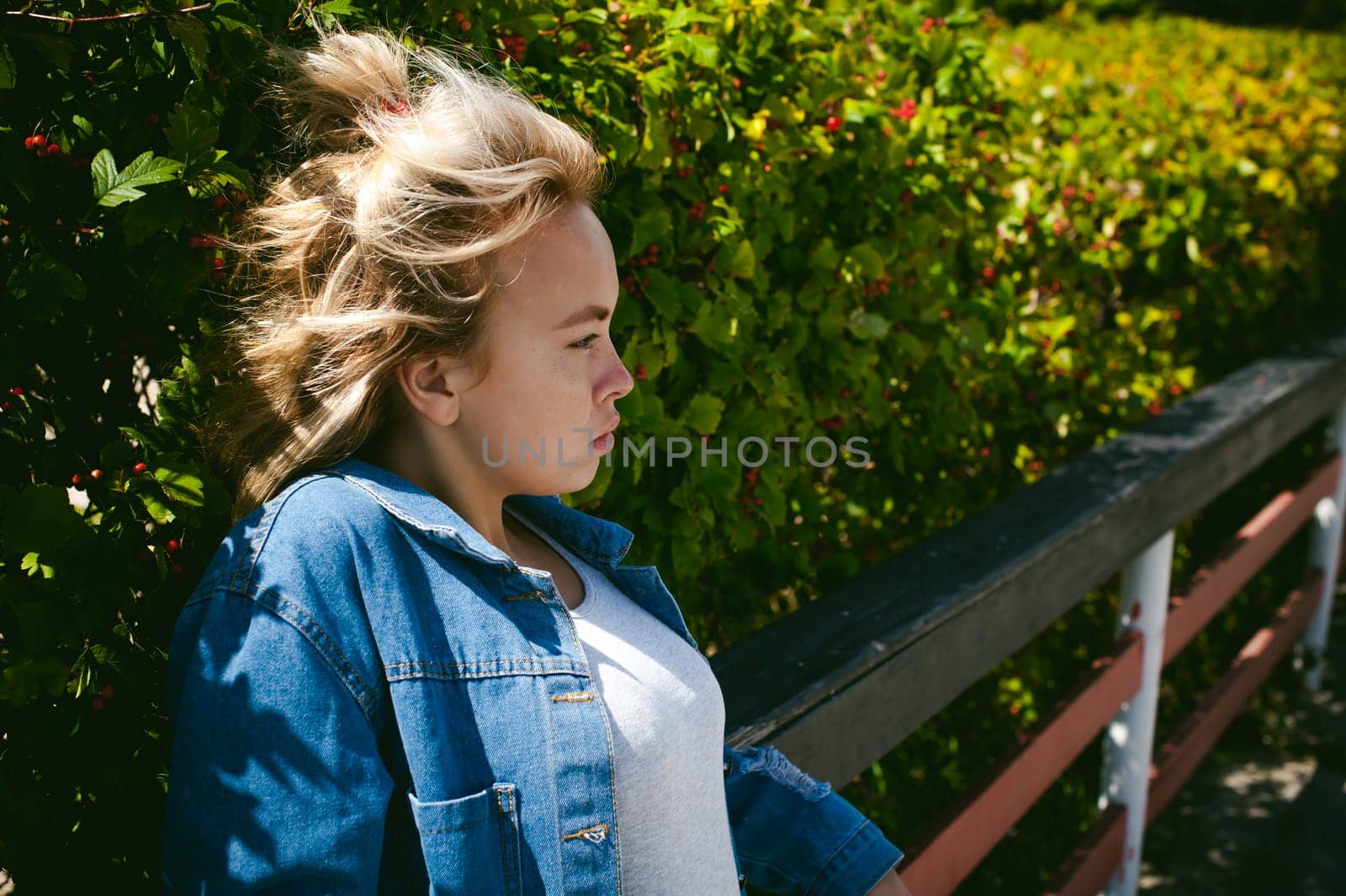 young beautiful woman in jeans clothes outdoors. portrait of a girl with freckles on her face, stylish girl on a sunny summer autumn day.