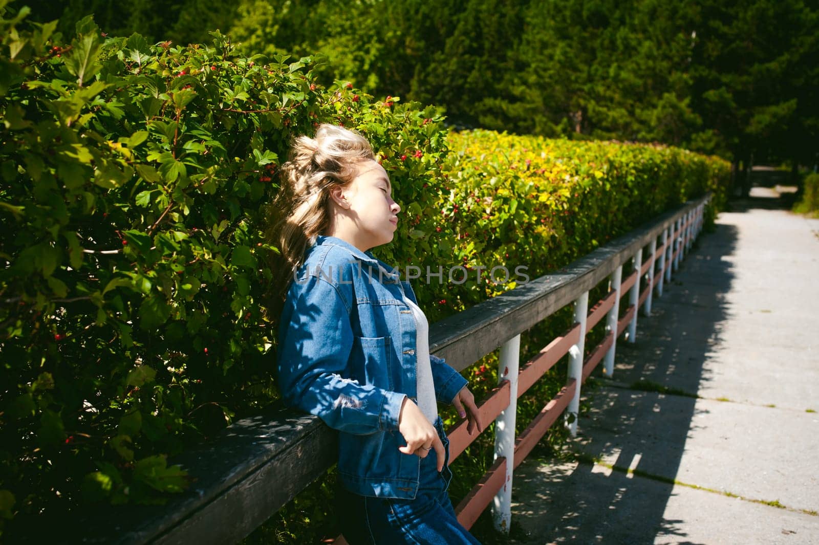 young beautiful woman in jeans clothes outdoors. portrait of a girl with freckles on her face, stylish girl on a sunny summer autumn day.