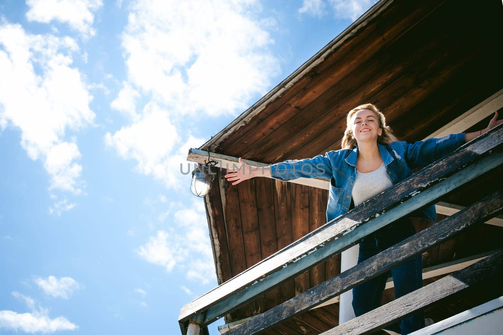 young beautiful woman in jeans clothes outdoors. portrait of a girl with freckles on her face, stylish girl on sea beach rescue tower, on a sunny summer autumn day. happy pulls hands to hug