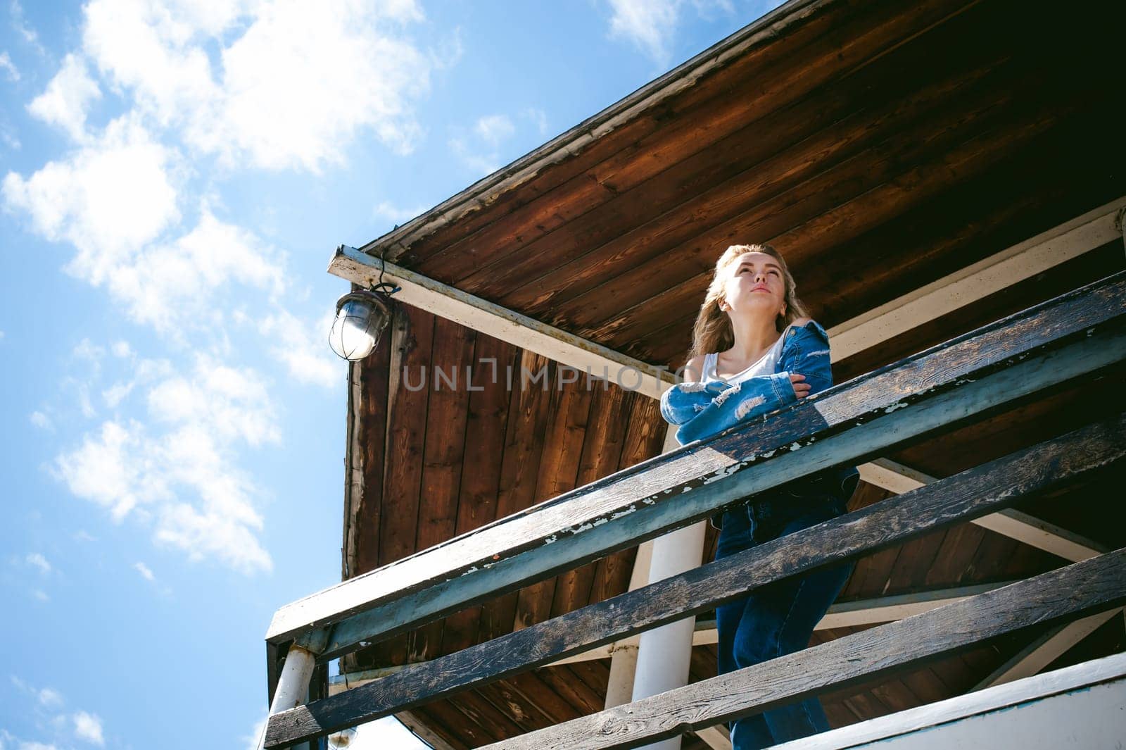 young beautiful woman in jeans clothes outdoors. portrait of a girl with freckles on her face, stylish girl on sea beach rescue tower, on a sunny summer autumn day.