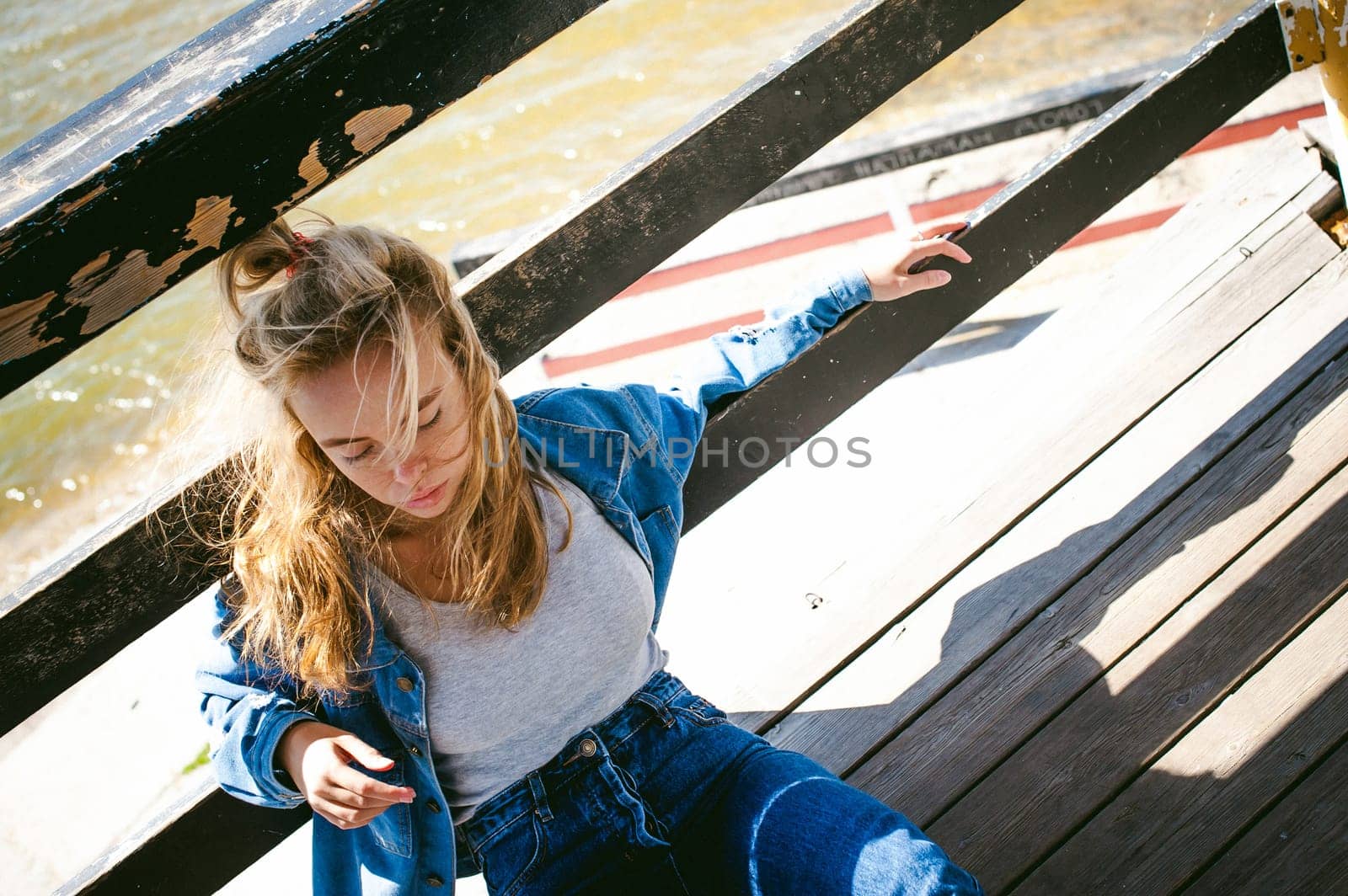 young beautiful woman in jeans clothes outdoors. portrait of a girl with freckles on her face, stylish girl on sea beach rescue tower, on a sunny summer autumn day.