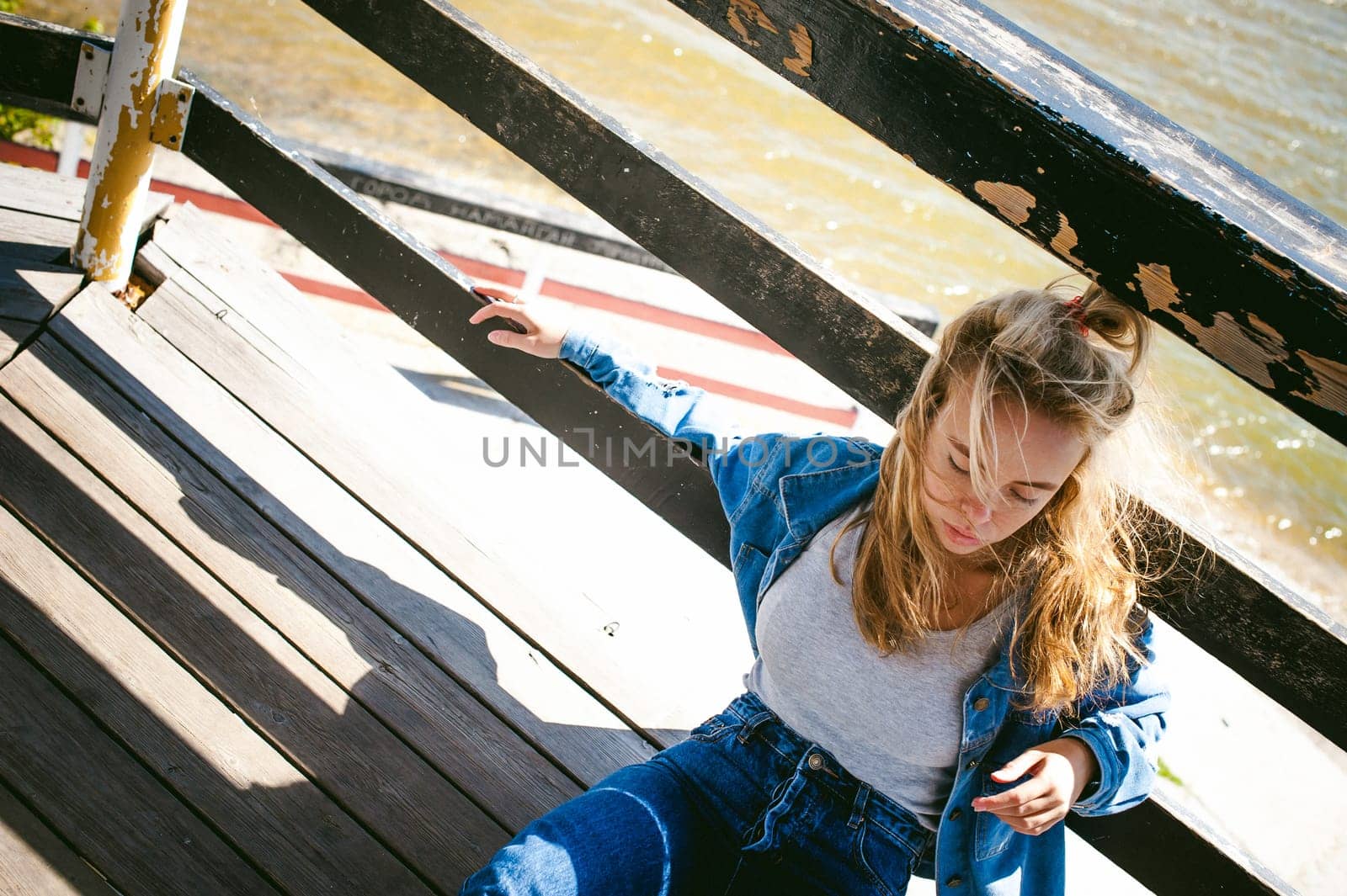 young beautiful woman in jeans clothes outdoors. portrait of a girl with freckles on her face, stylish girl on sea beach rescue tower, on a sunny summer autumn day.