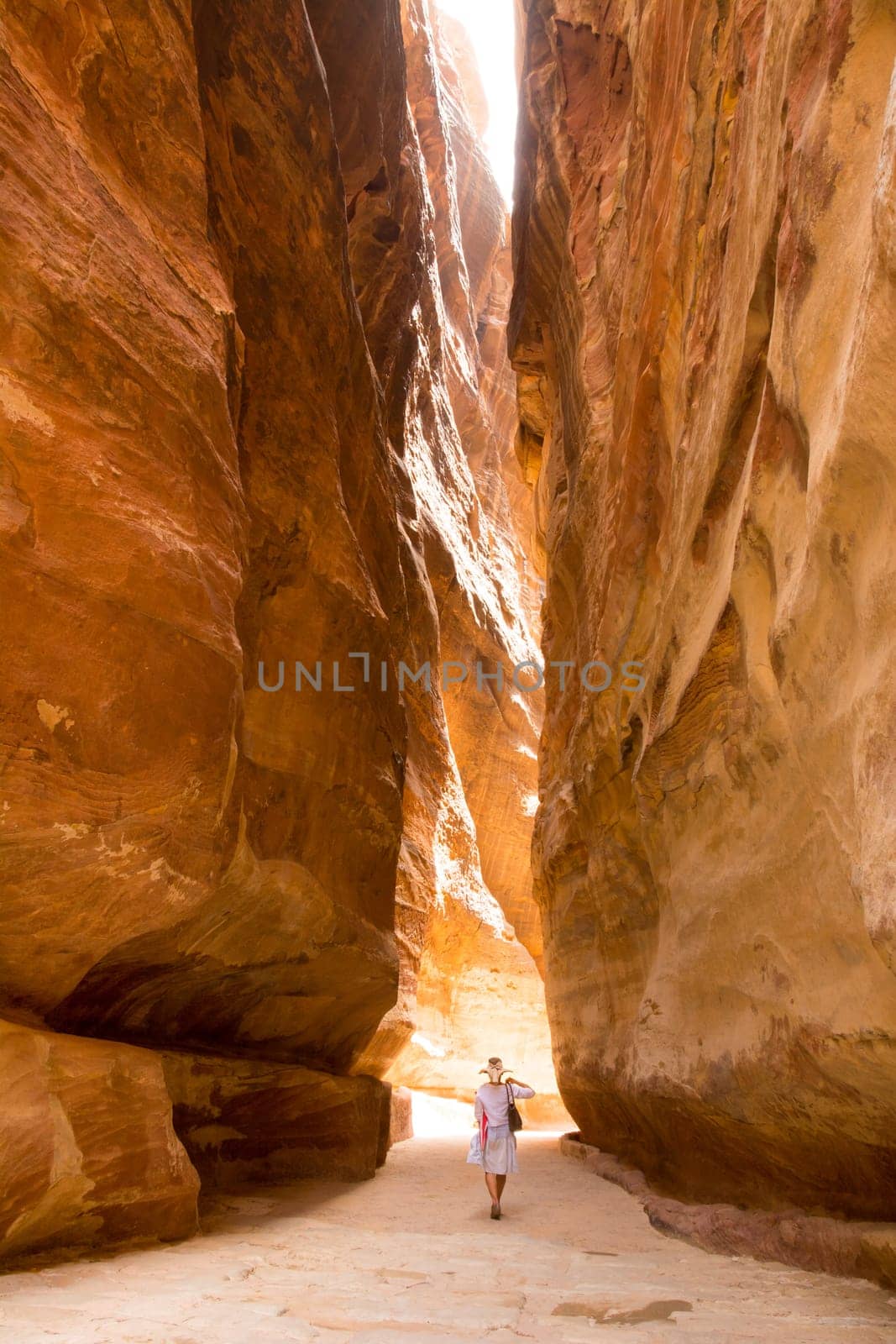 PETRA, JORDAN - APRIL 25, 2016: A narrow passage between steep rock formations in the siq at Petra the ancient City Al Khazneh in Jordan lit by the sun