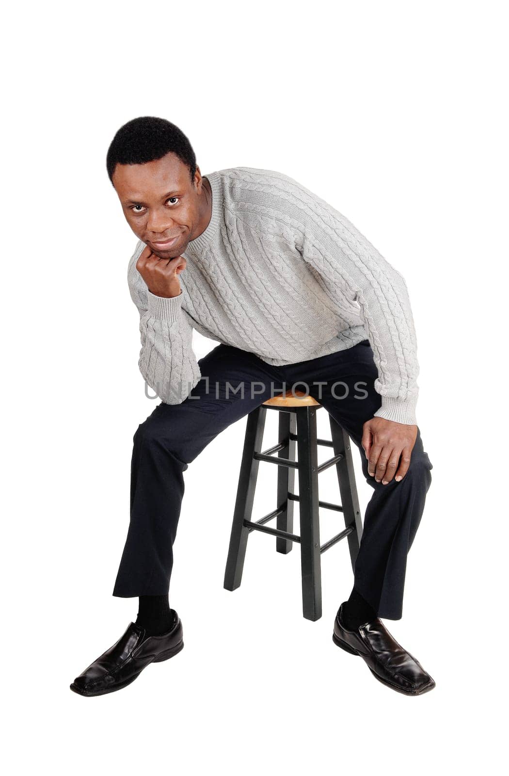 A full body image of a African American man in dress pants and sweater.sitting on chair with his hand on the chin, isolated for white background.