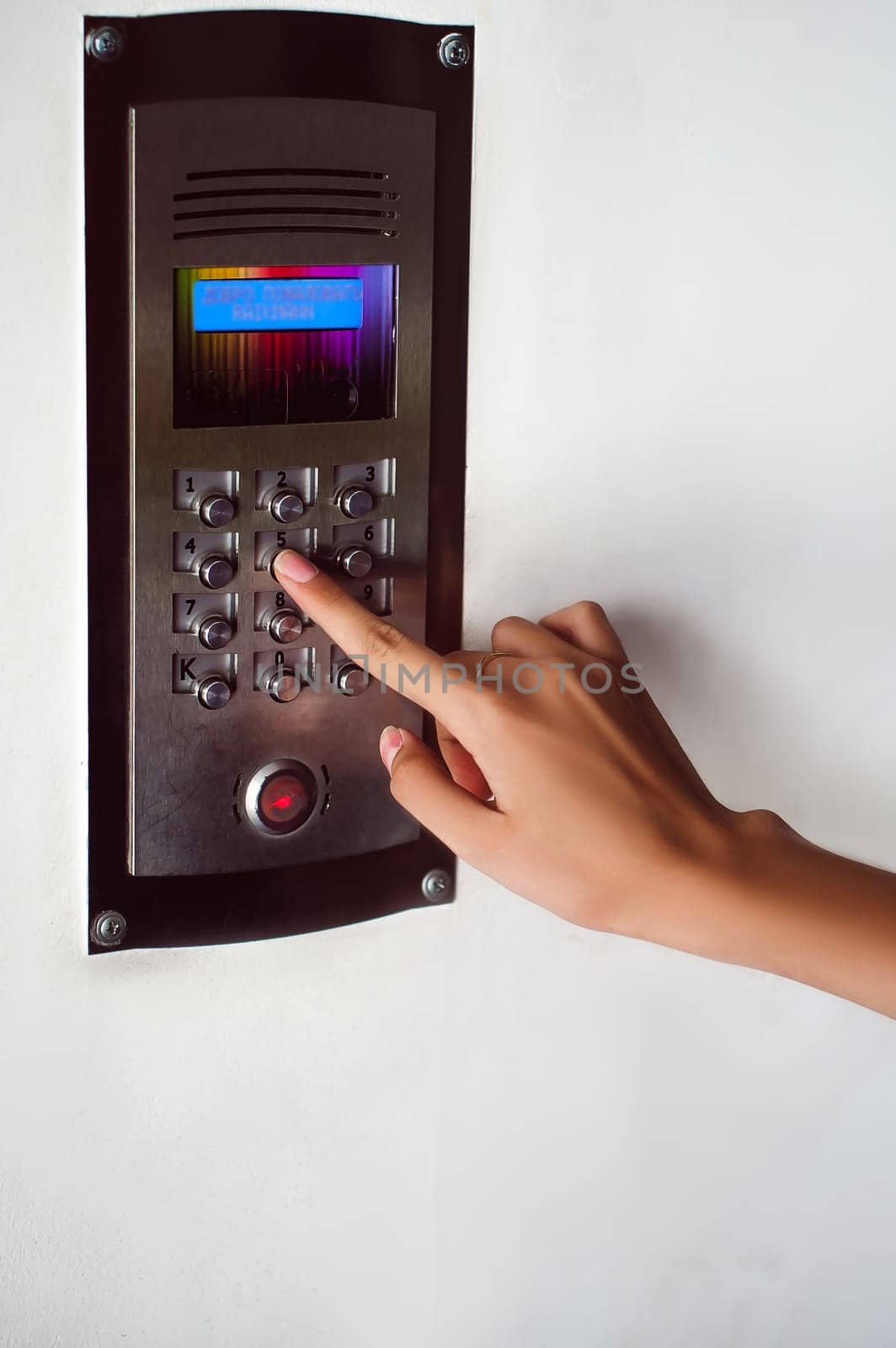 attractive woman in a blue elegant dress, dials code into intercom, at entrance of house