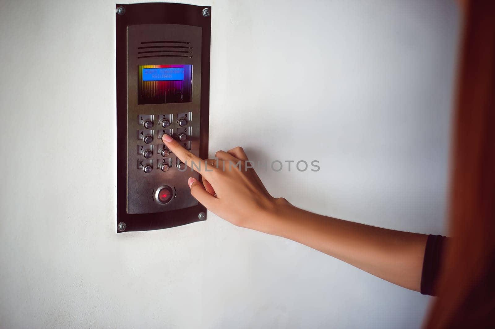 attractive woman in a blue elegant dress, dials code into intercom, at entrance of house