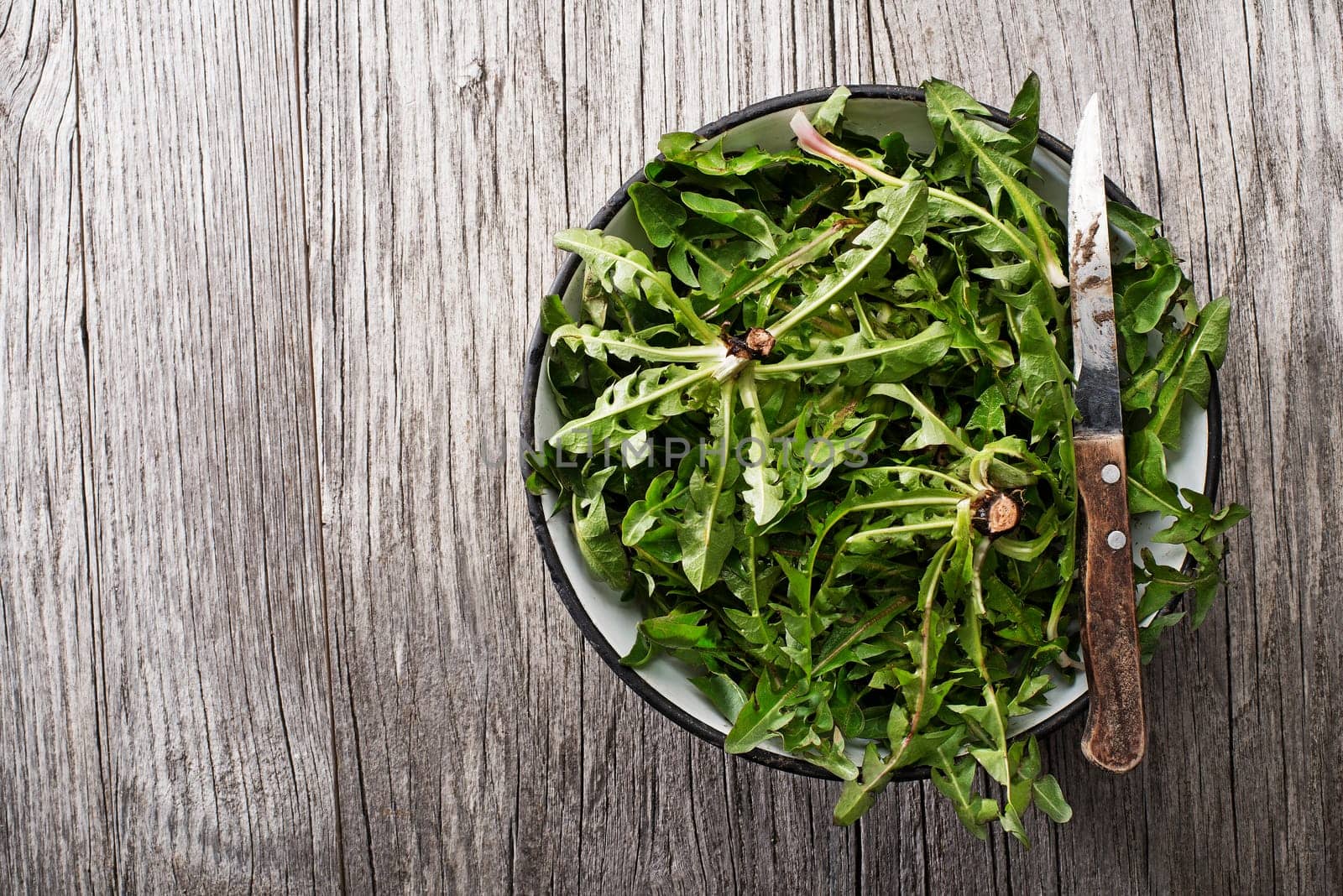 Fresh dandelion leaves on wooden background overhead shoot