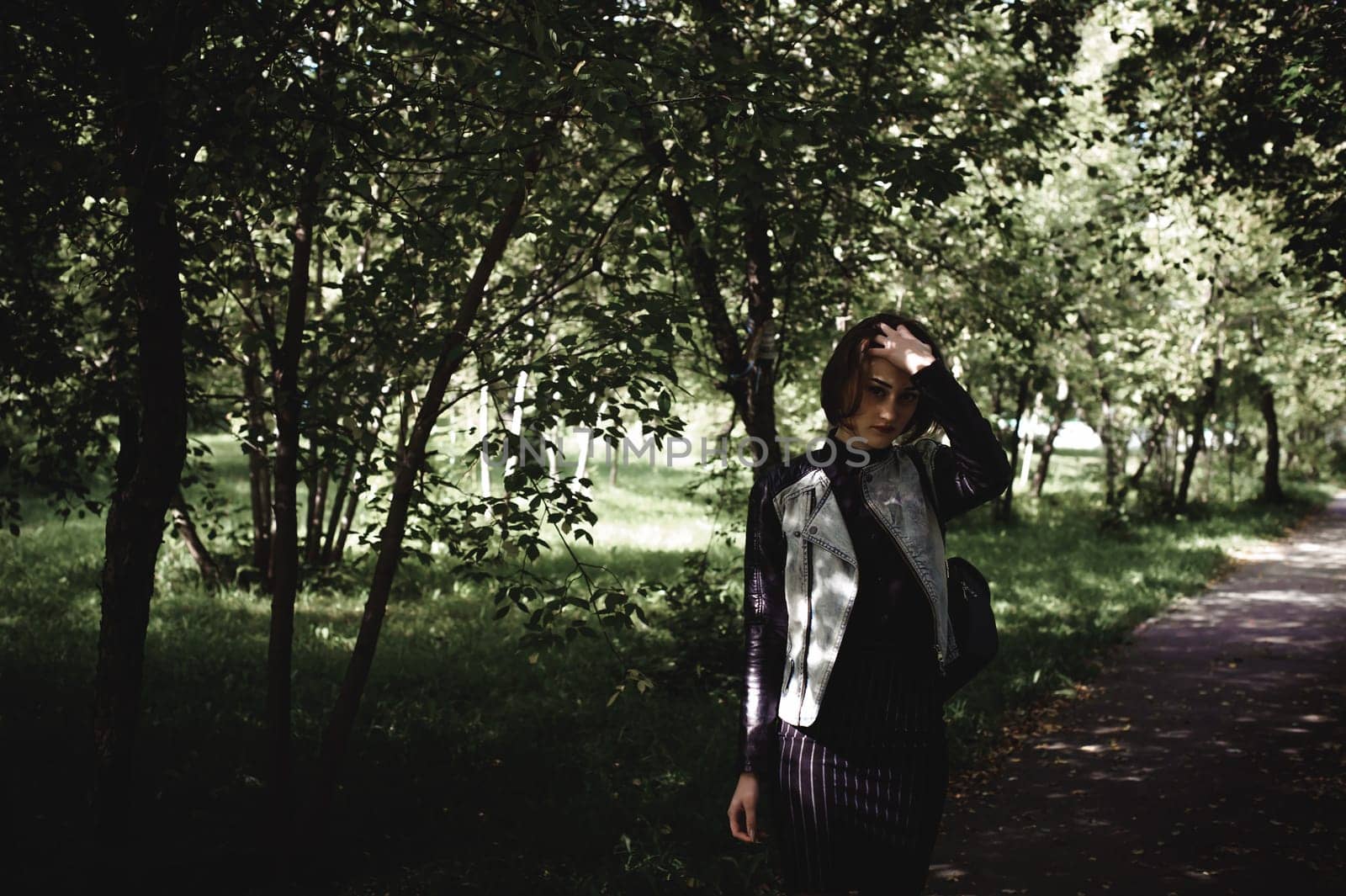 street portrait of a girl student, fashionably dressed in dark clothes, with a black backpack and denim jacket autumn sunny day
