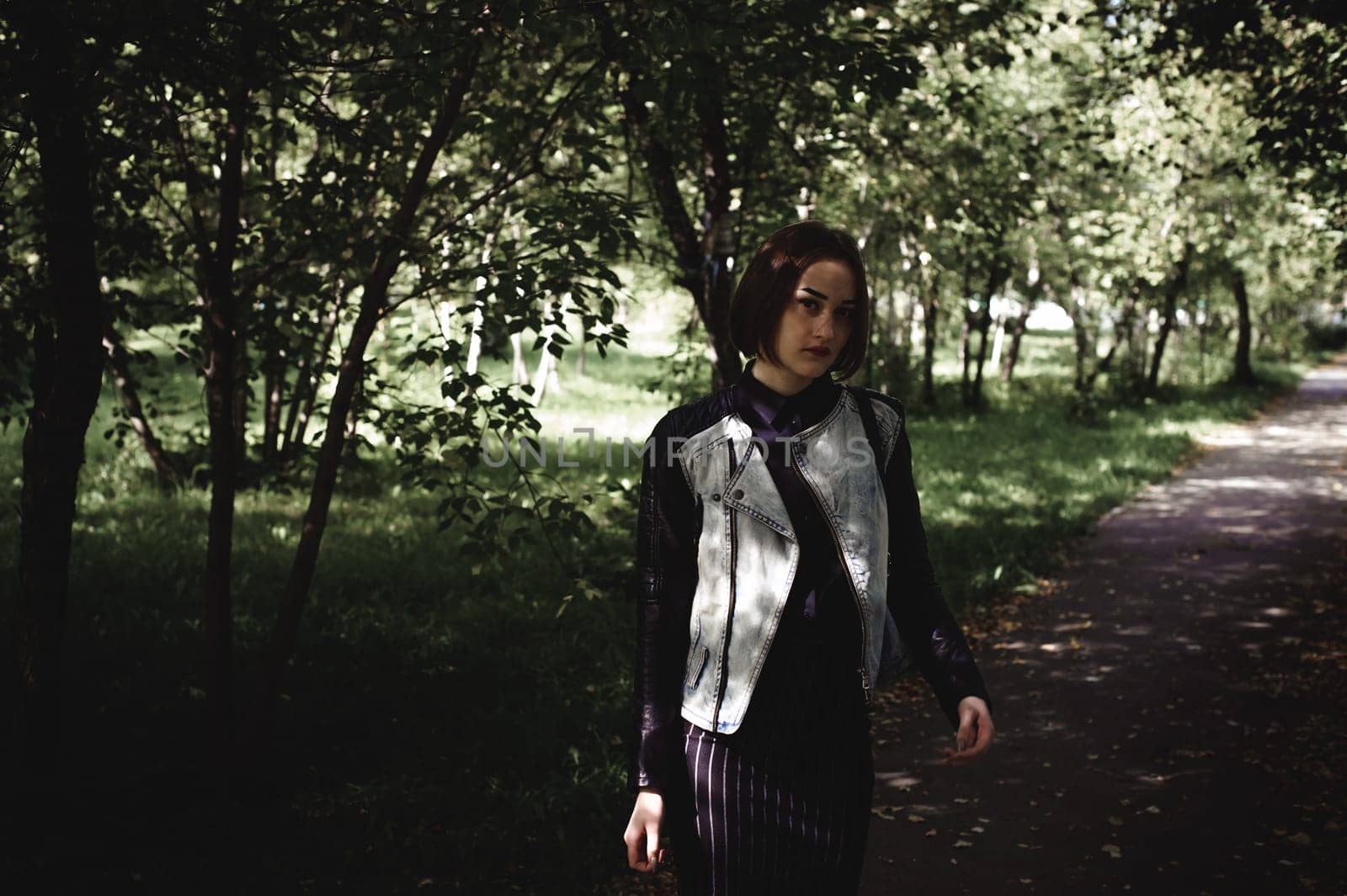 street portrait of a girl student, fashionably dressed in dark clothes, with a black backpack and denim jacket autumn sunny day