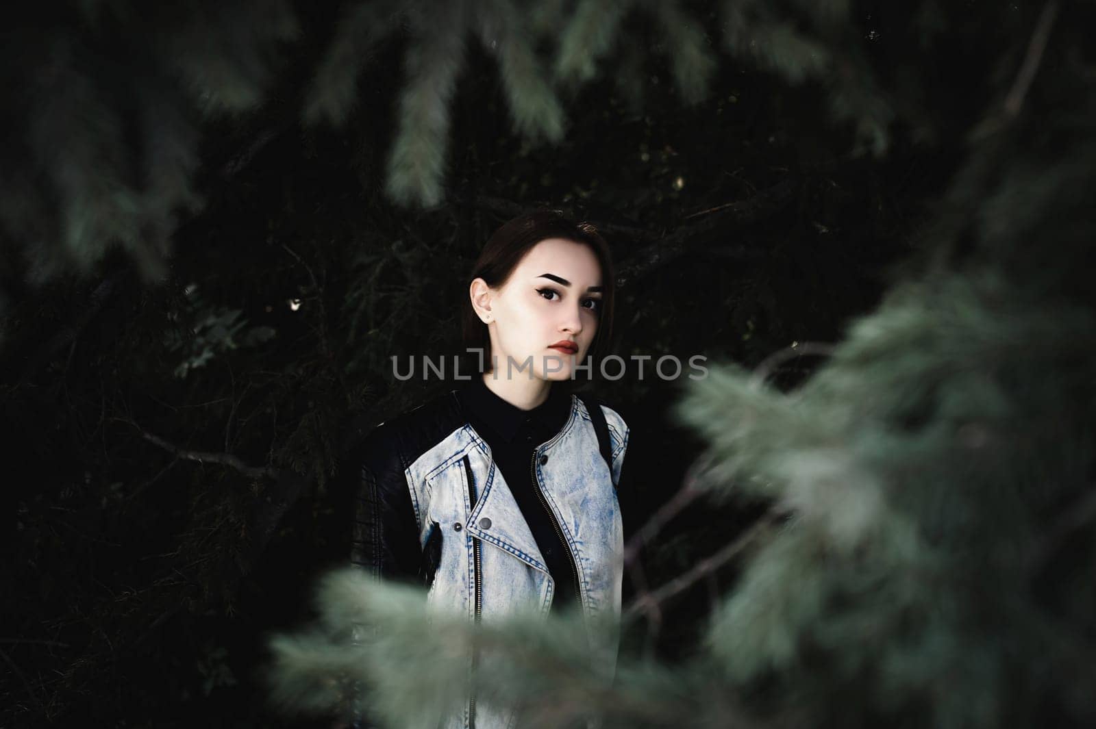 street portrait of a girl student, fashionably dressed in dark clothes, with a black backpack and denim jacket autumn sunny day