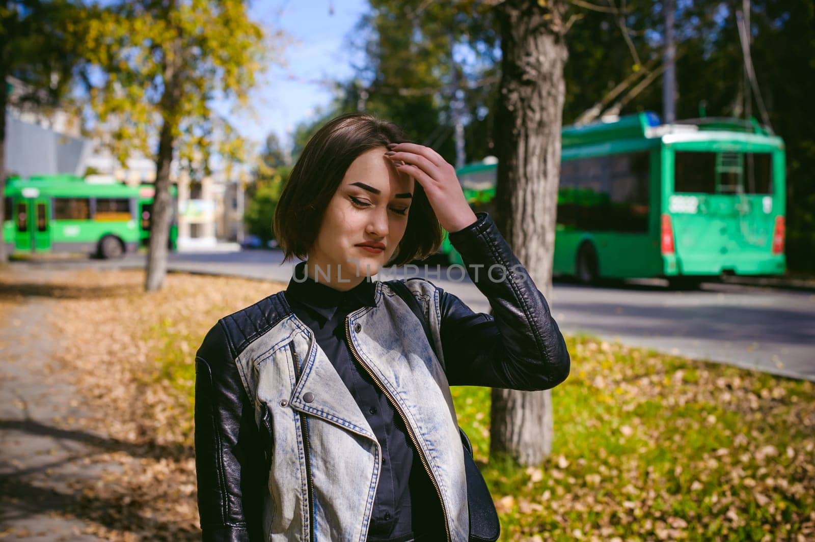 street portrait of a girl student, fashionably dressed in dark clothes, with a black backpack and denim jacket autumn sunny day