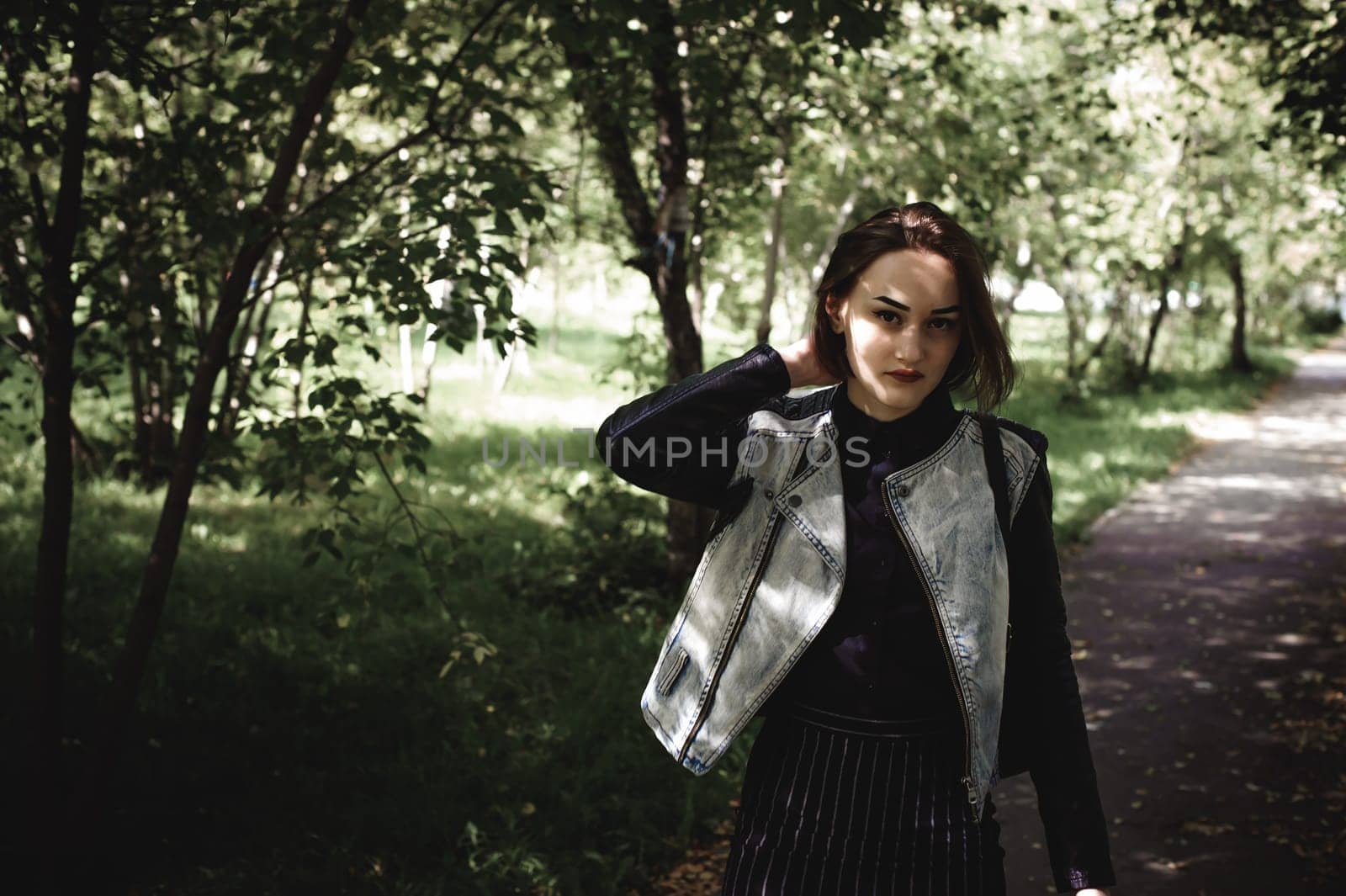 street portrait of a girl student, fashionably dressed in dark clothes, with a black backpack and denim jacket autumn sunny day