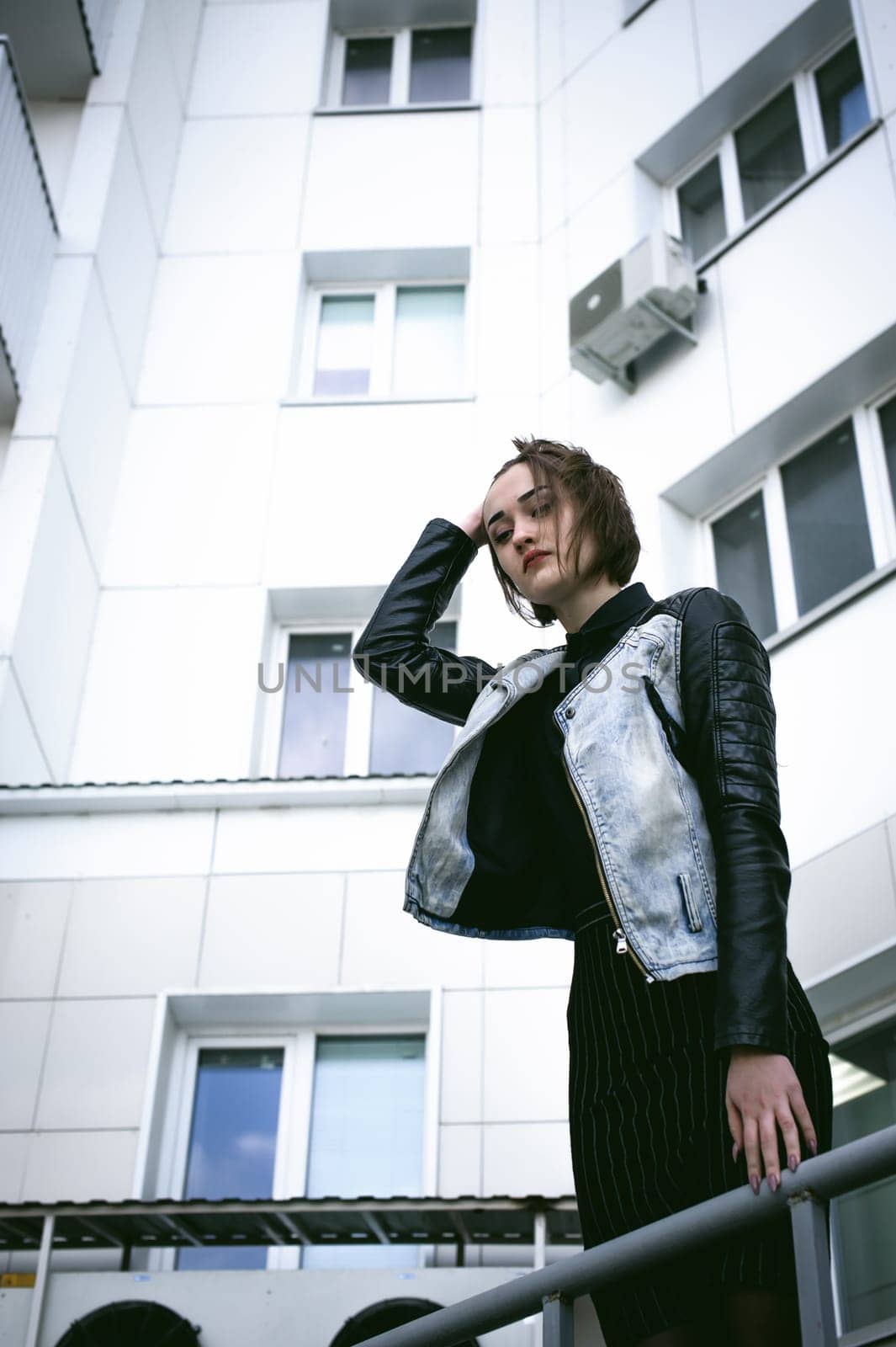 street portrait of a girl student, fashionably dressed in dark clothes, with a black backpack and denim jacket autumn sunny day