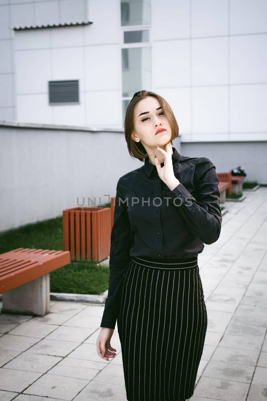 street portrait of a student girl dressed fashionably in dark clothes, on an autumn sunny day