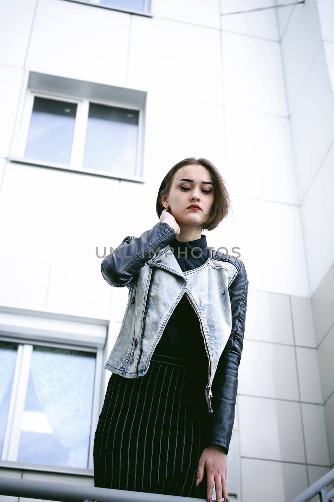 street portrait of a girl student, fashionably dressed in dark clothes, with a black backpack and denim jacket autumn sunny day