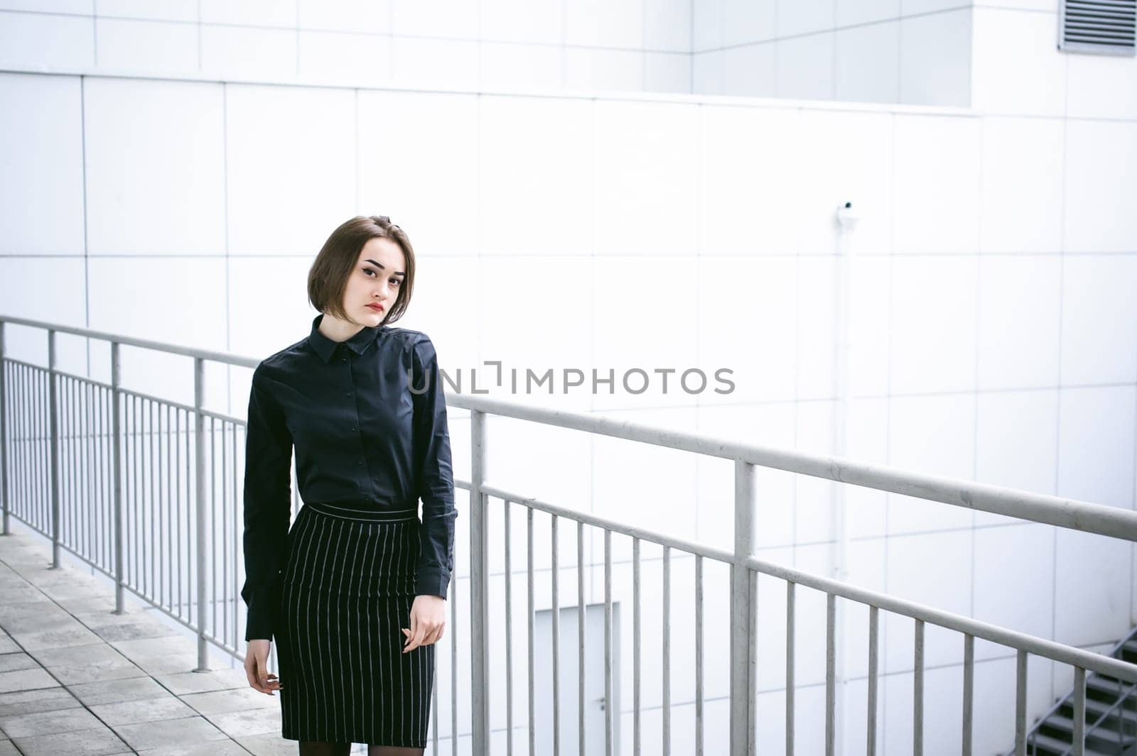 street portrait of a student girl dressed fashionably in dark clothes, on an autumn sunny day