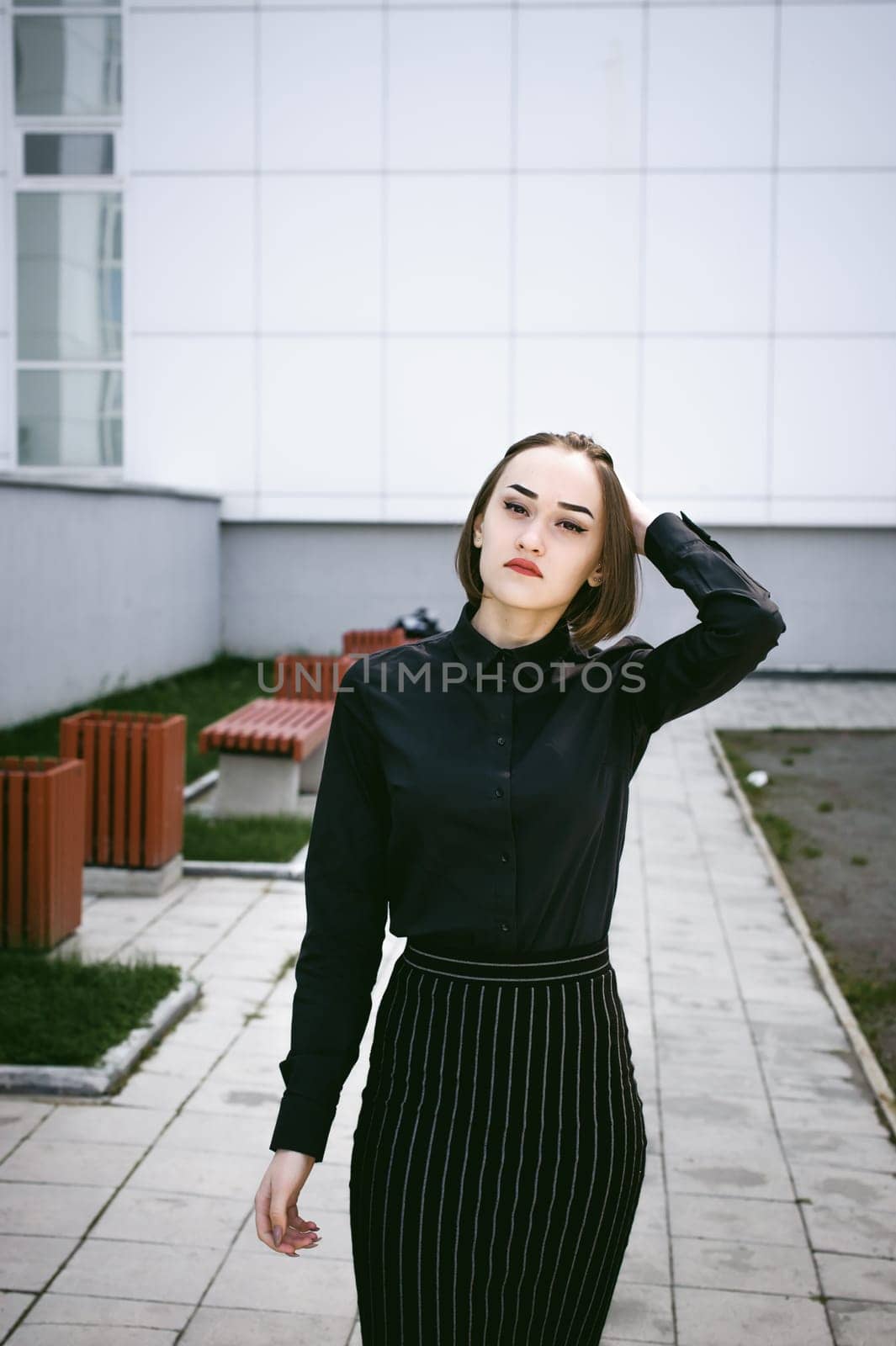 street portrait of a student girl dressed fashionably in dark clothes, on an autumn sunny day