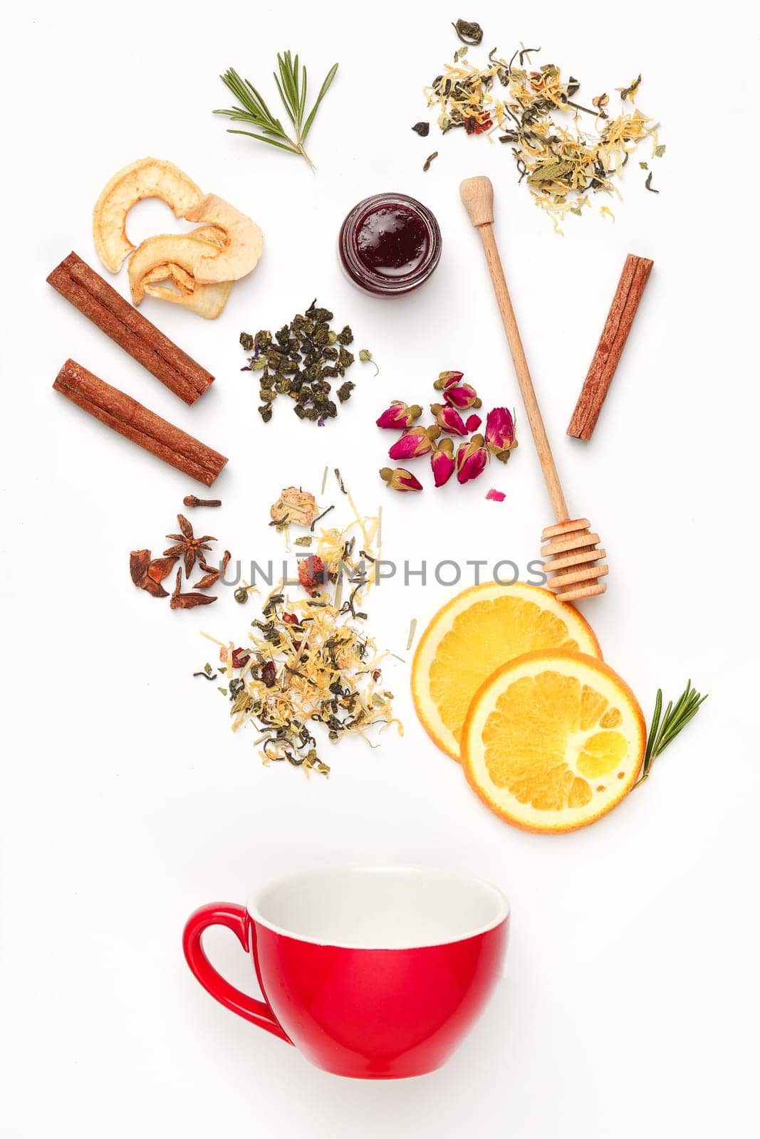 Beautiful and delicious dried tea leaves with herbs, flowers, berries, fruits falling in cup of tea over white background