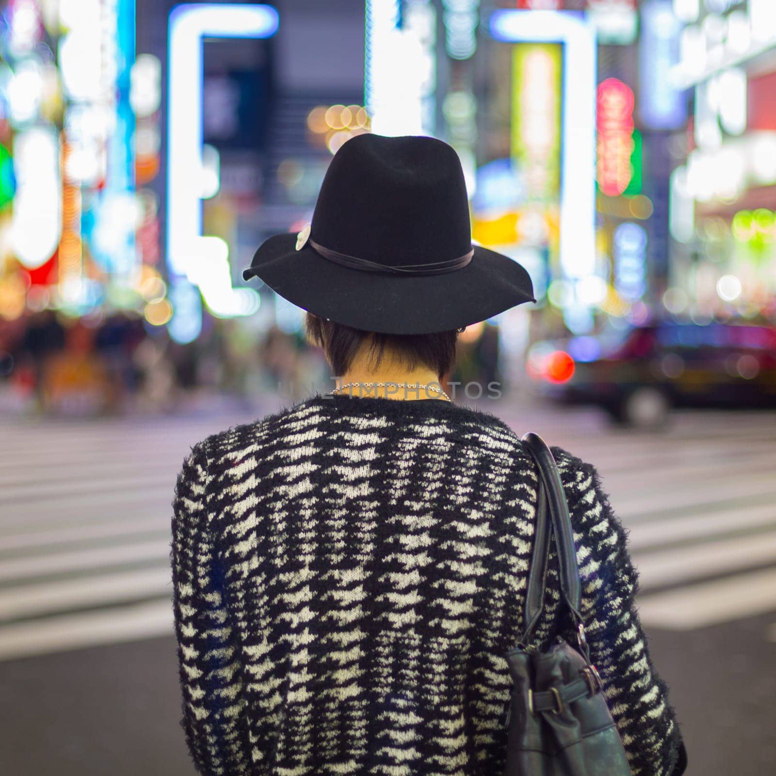 Solitary fashionably dressed young man waiting on crossroad in Kabukicho, entertainment and red-light district in Shinjuku, Tokyo, Japan.