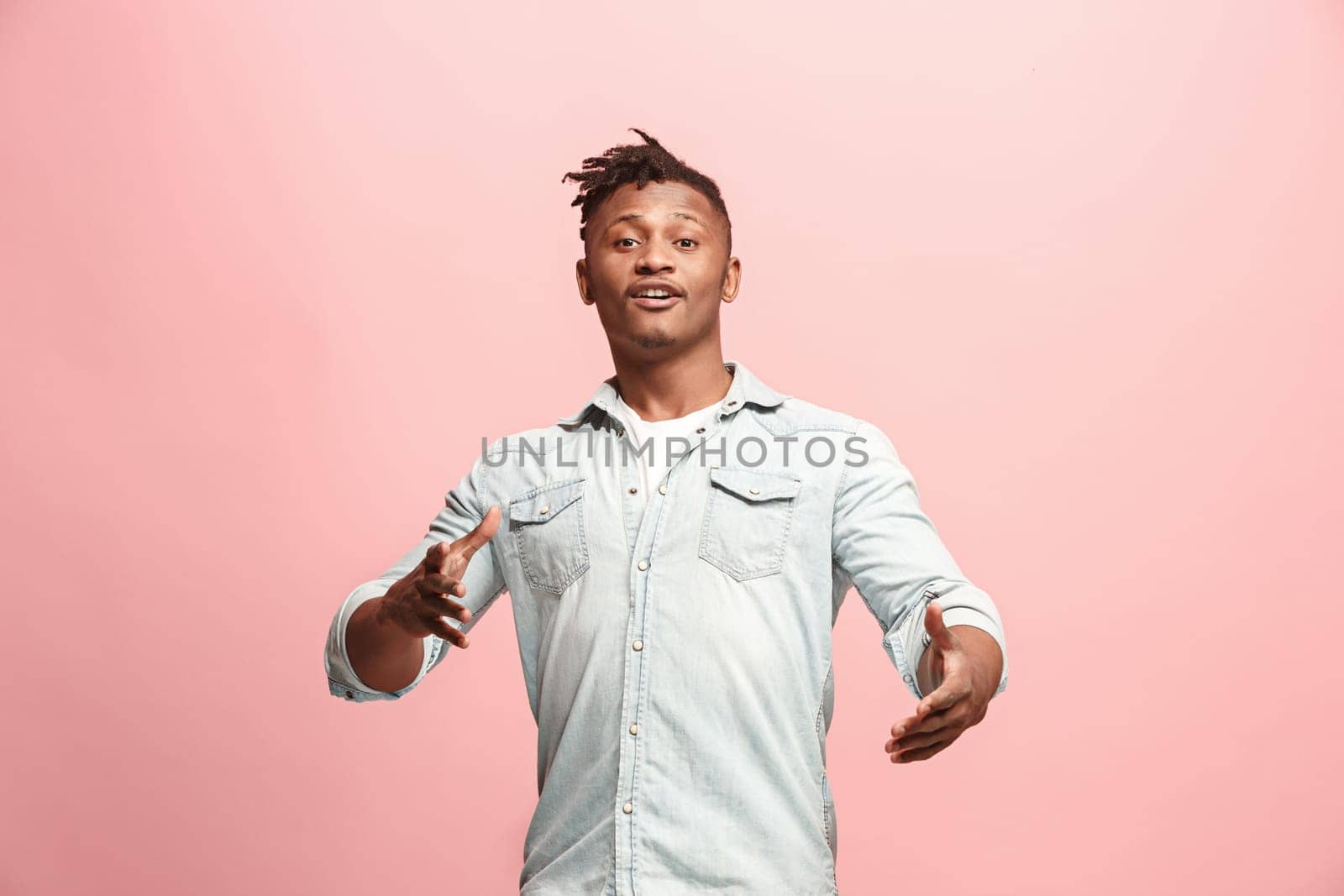 Delight. African american male half-length front portrait isolated on pink studio backgroud. Young, emotional, smiling, surprised man standing. Human emotions, facial expression concept. Trendy colors