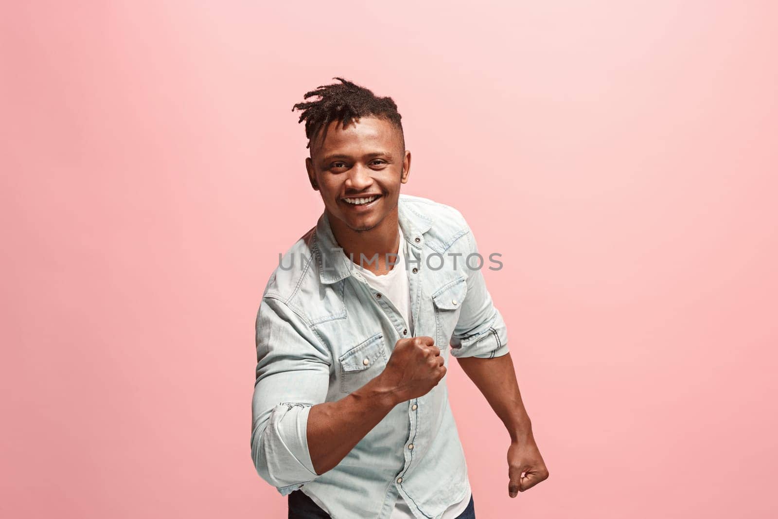 I won. Winning success happy man celebrating being a winner. Dynamic image of afro-american male model on pink studio background. Victory, delight concept. Human facial emotions concept. Trendy colors