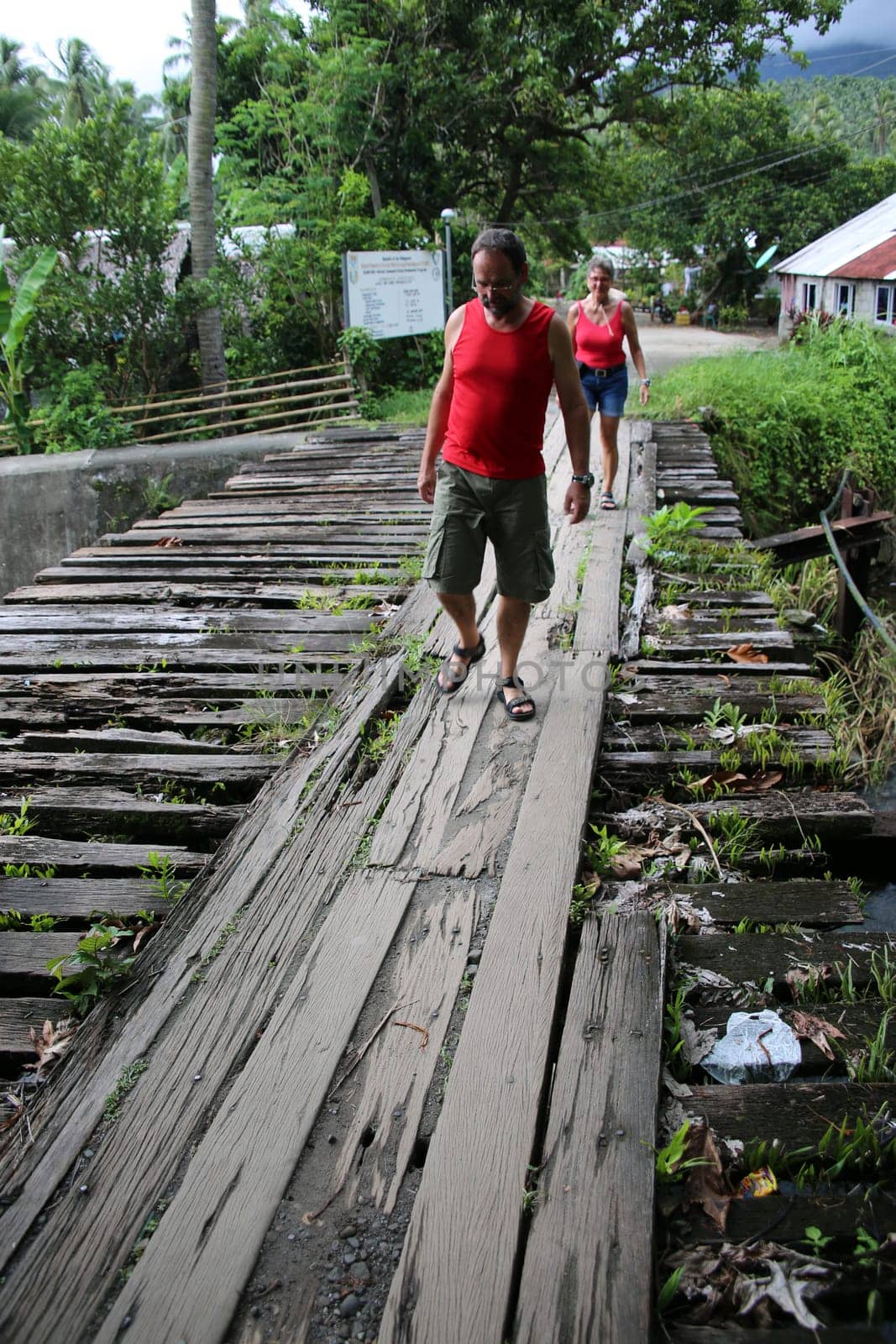 Tourists cross a creek on a dilapidated wooden bridge,Pintuyan,Panaon Island,Southern Leyte,Philippines