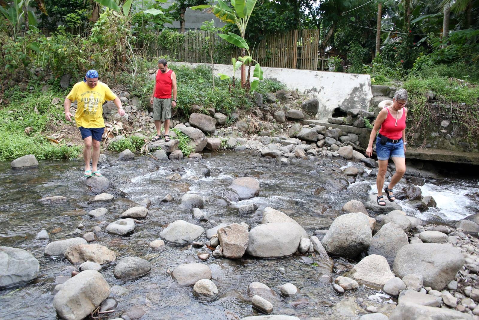 Tourists cross a stream over stones in the water,Pintuyan,Panaon Island,Southern Leyte,Philippines