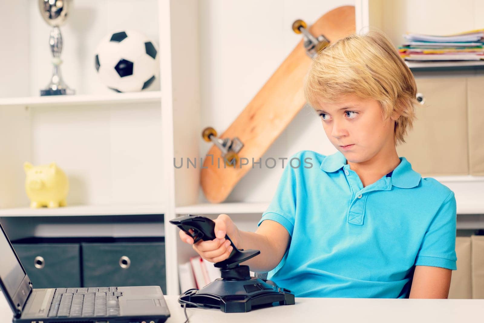 blond boy is playing computer game in his room