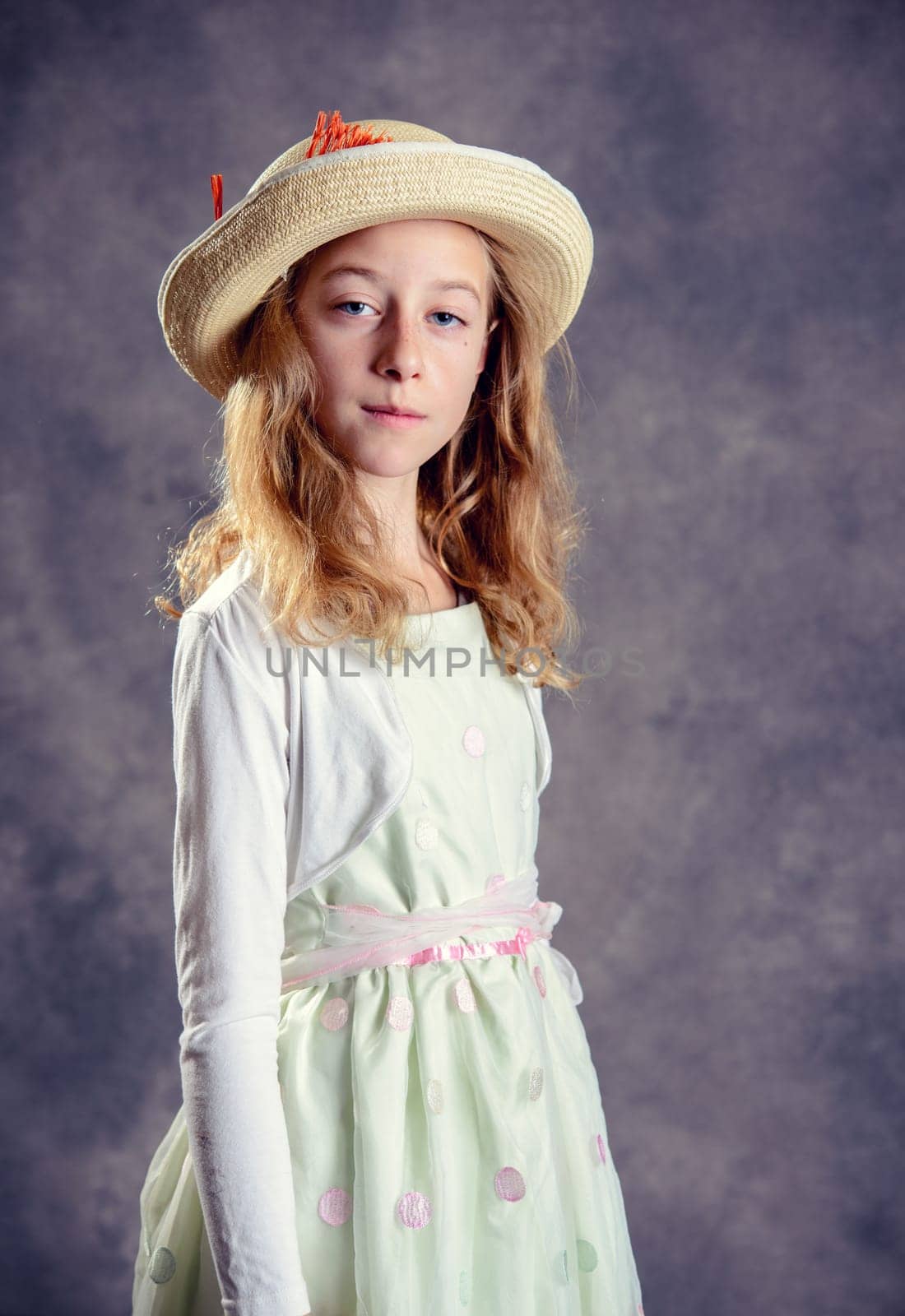 nice girl with blond hair in white dress and straw hat looking in to the camera