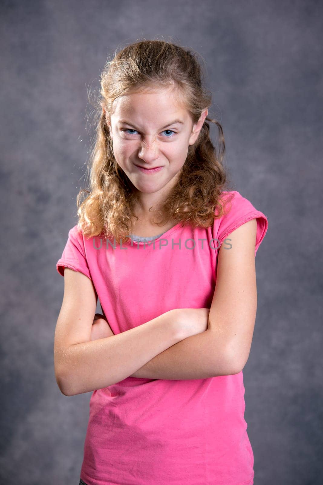 angry girl with blond hair and pink shirt in front of gray background