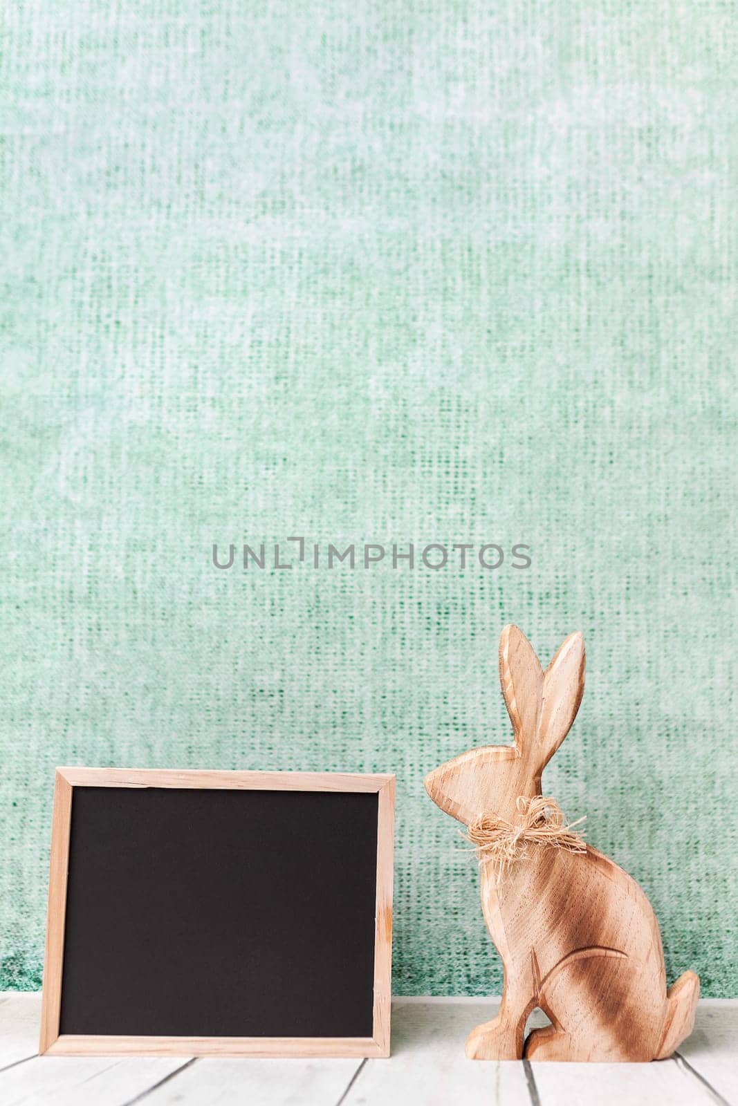 Traditional wooden Easter holiday bunny and an empty blackboard