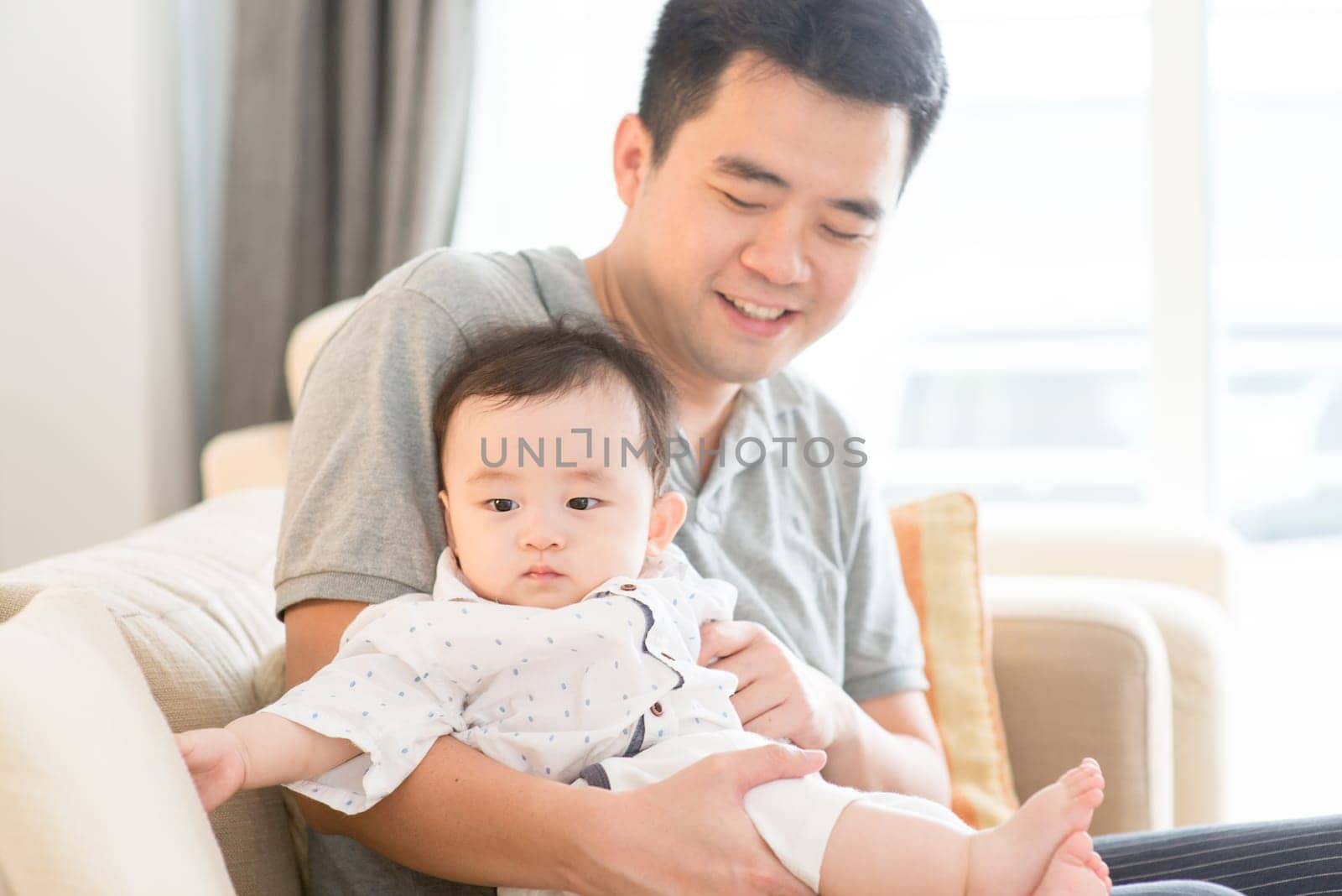 Asian family at home. Father babysitting son, living lifestyle indoors.