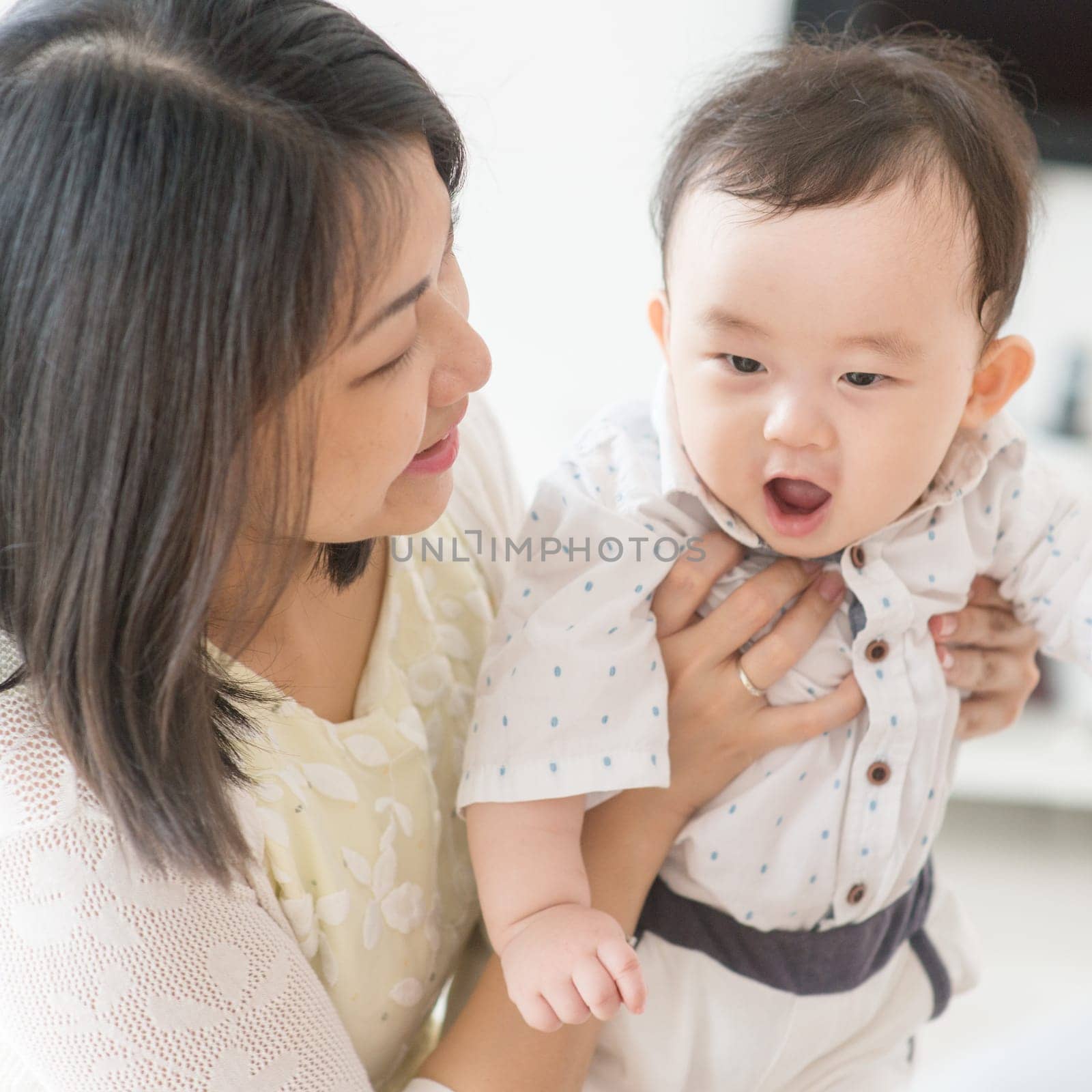 Mother playing with 9 months old baby. Asian family at home, living lifestyle indoors.