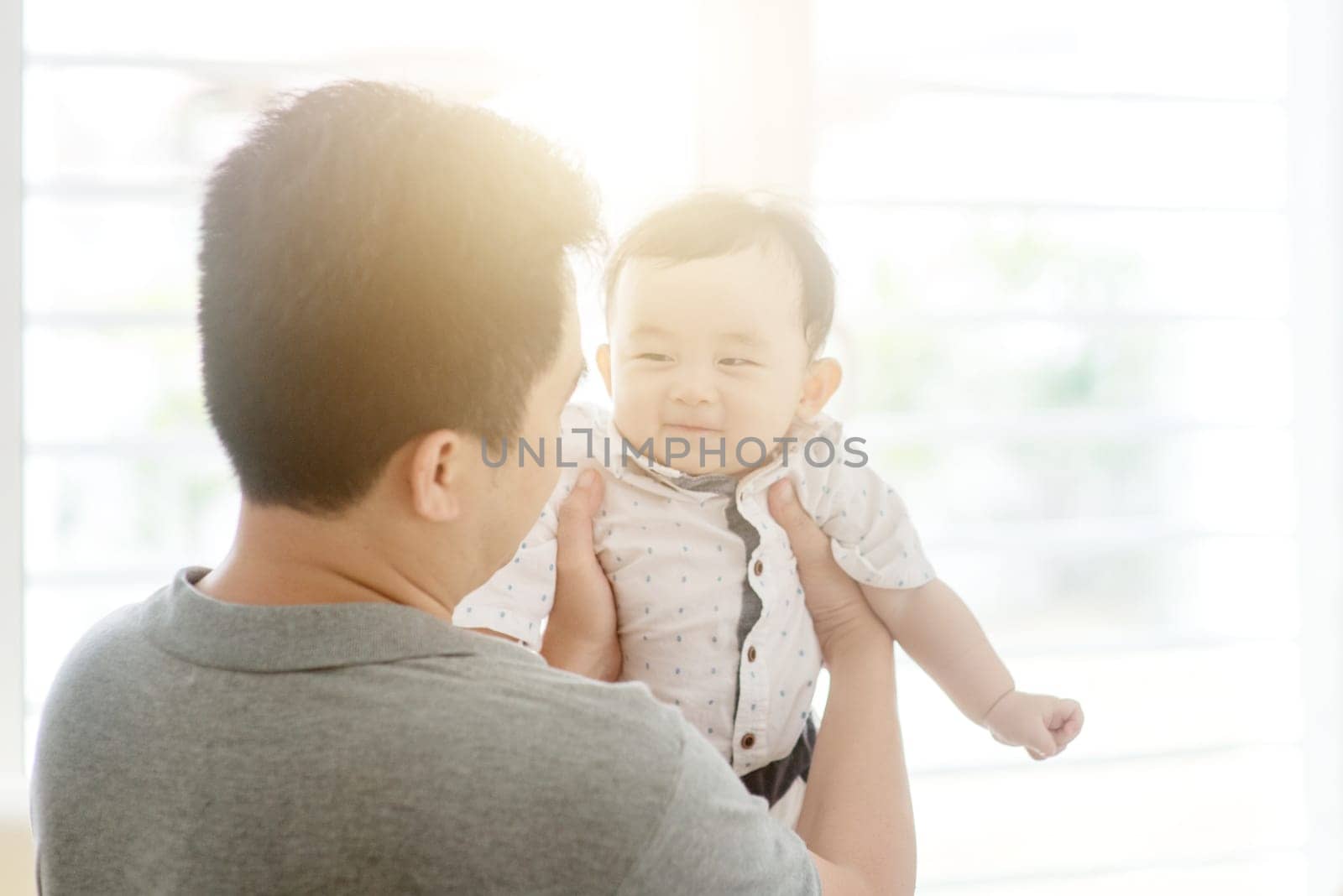 Happy Asian family at home. Father holding child, living lifestyle indoors.