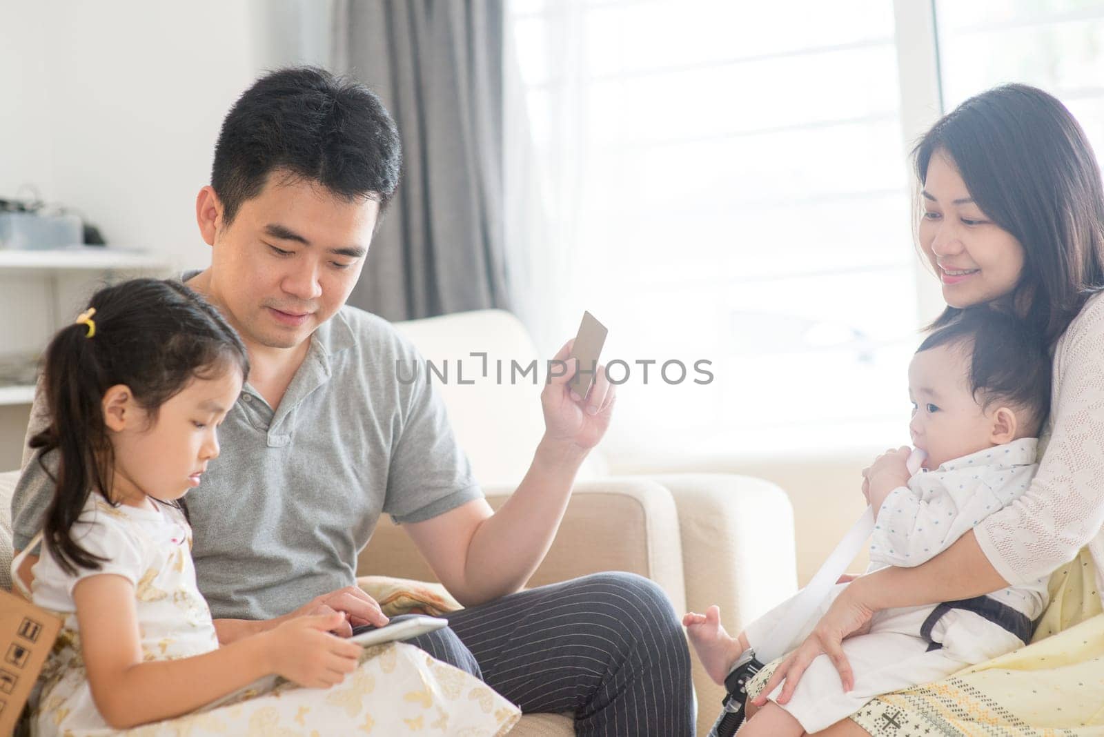 Online shopping with digital tablet pc and credit card. Happy Asian family at home, natural living lifestyle indoors.